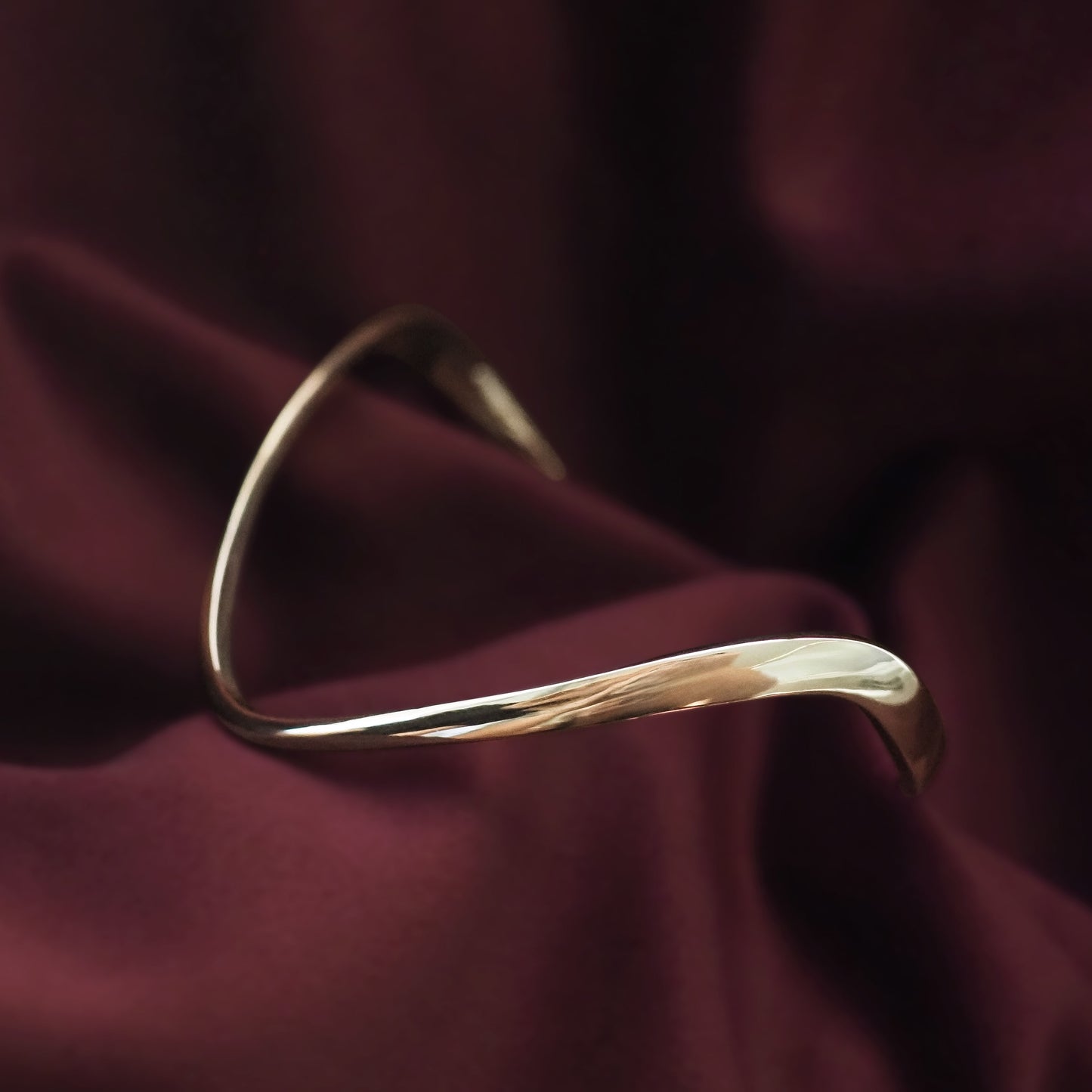 Gold bracelet on a dark red fabric background