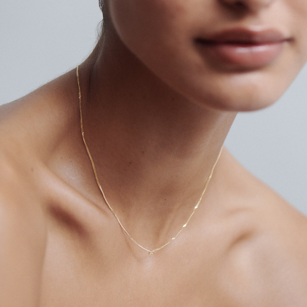 Close-up of a woman wearing a delicate gold chain necklace on bare skin, showcasing minimalist luxury jewellery.
