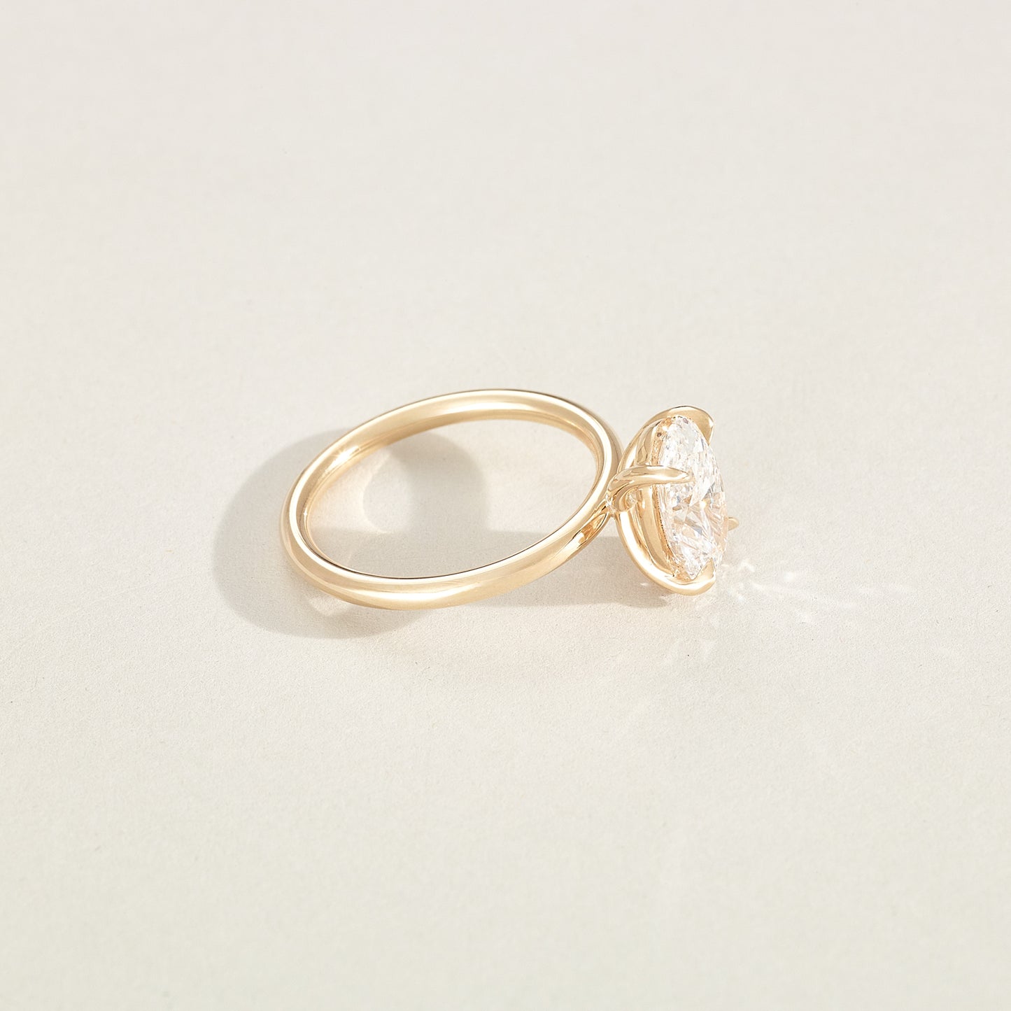 Gold ring with a diamond on a light beige background