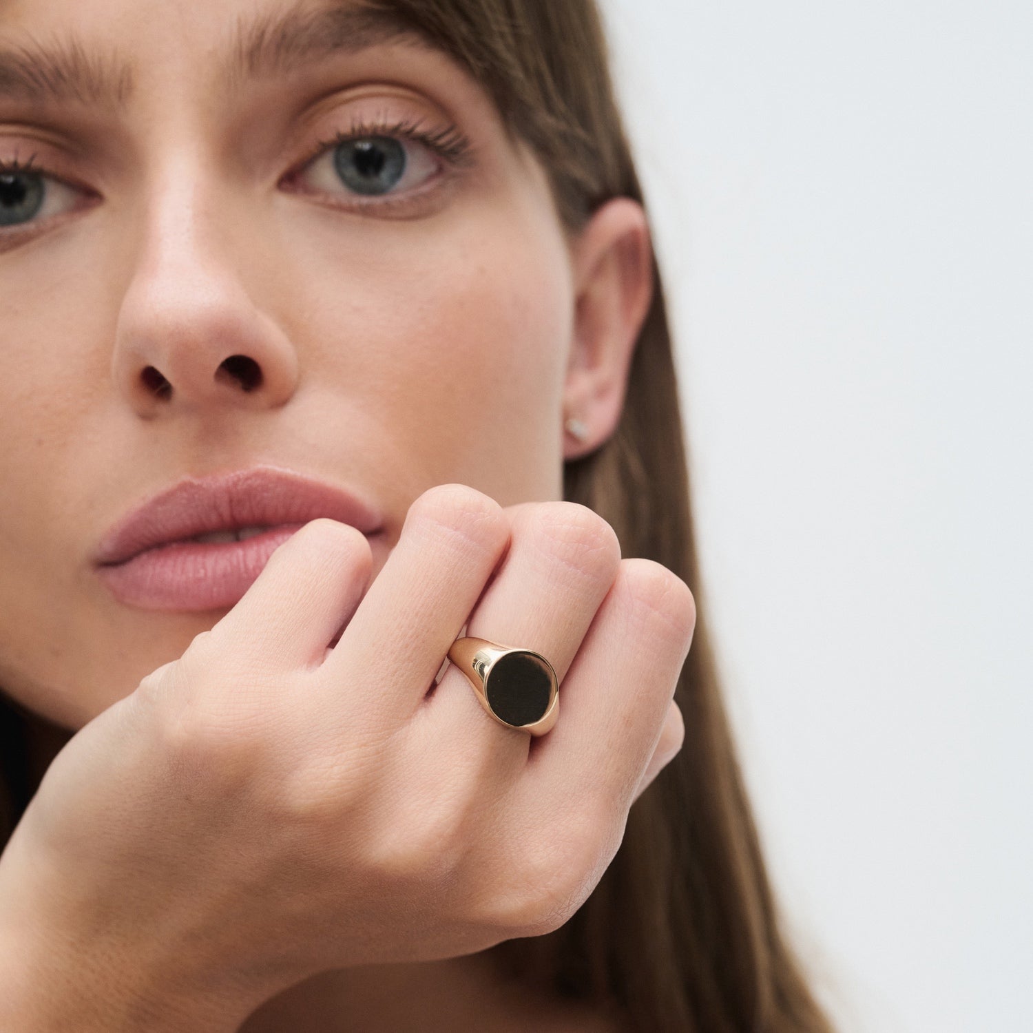Woman with a gold ring featuring a large black stone on her finger, close-up portrait style. Luxurious jewellery focus.