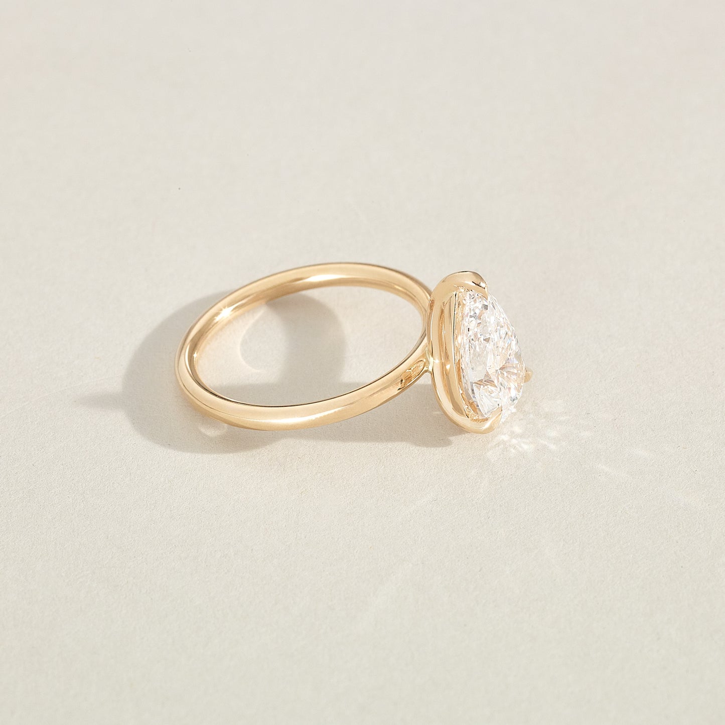 Gold ring with a diamond on a light beige background