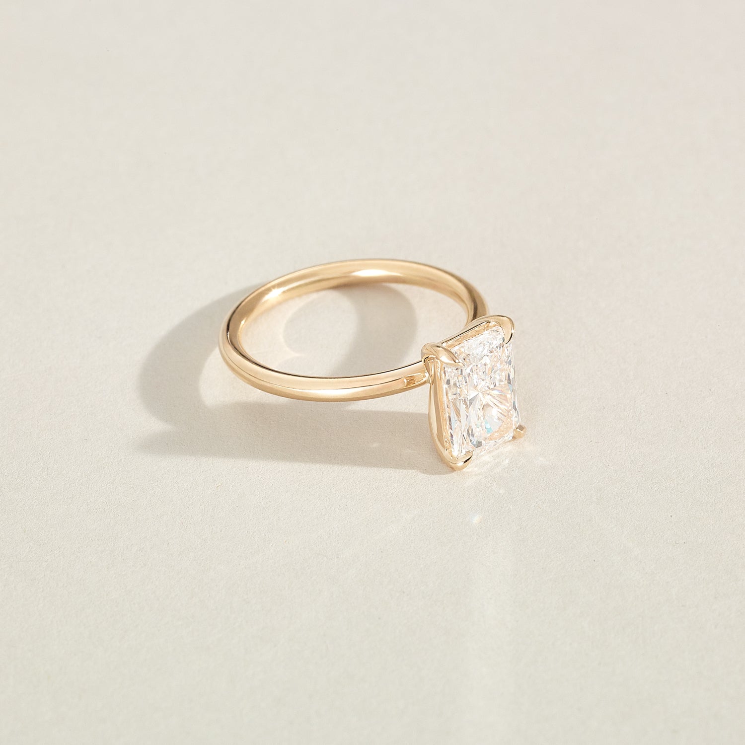 Gold ring with a diamond on a light beige background