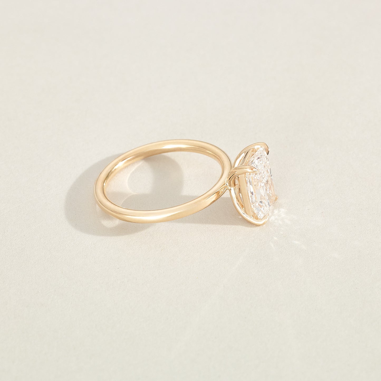 Gold ring with a diamond on a light beige background