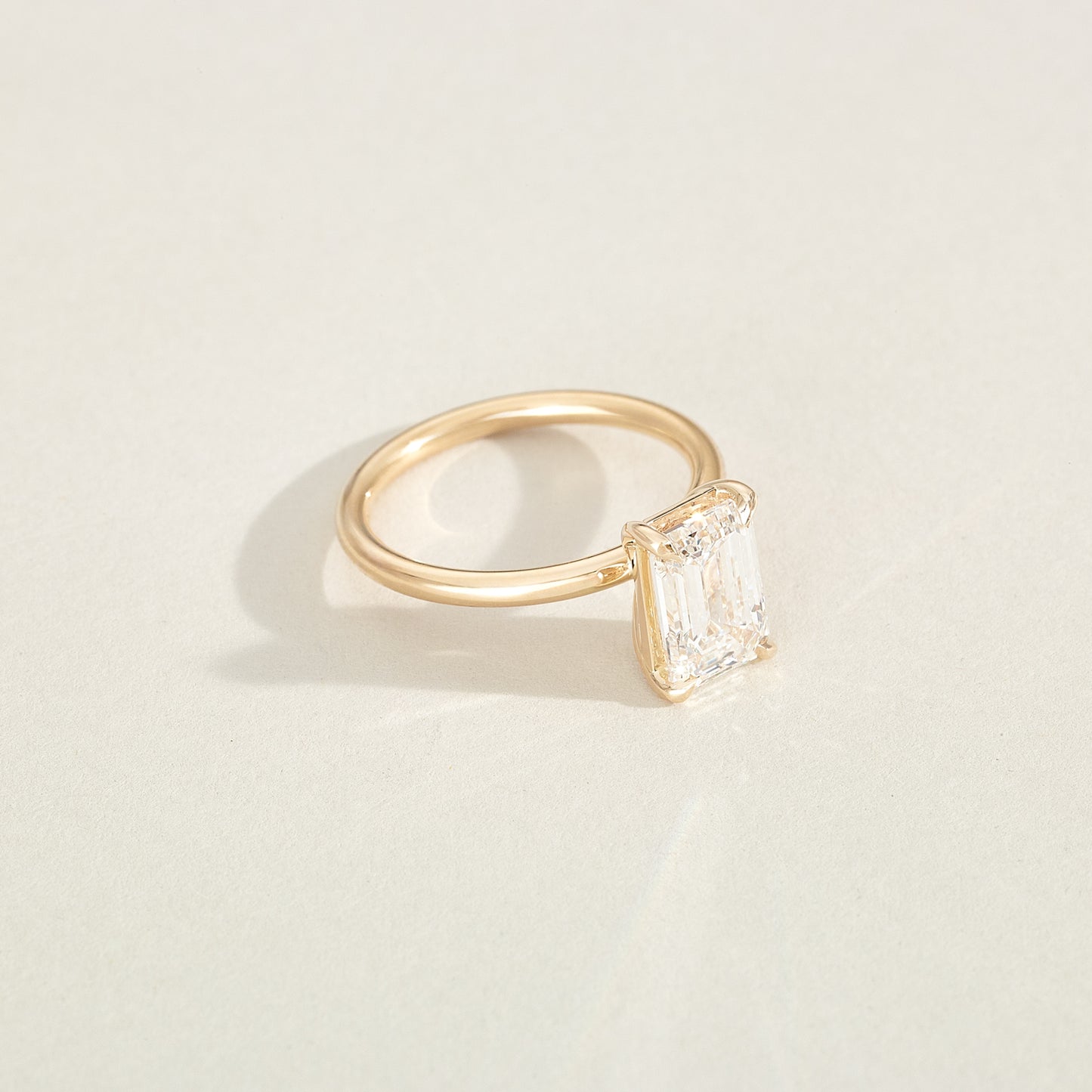 Gold ring with a diamond on a light beige background