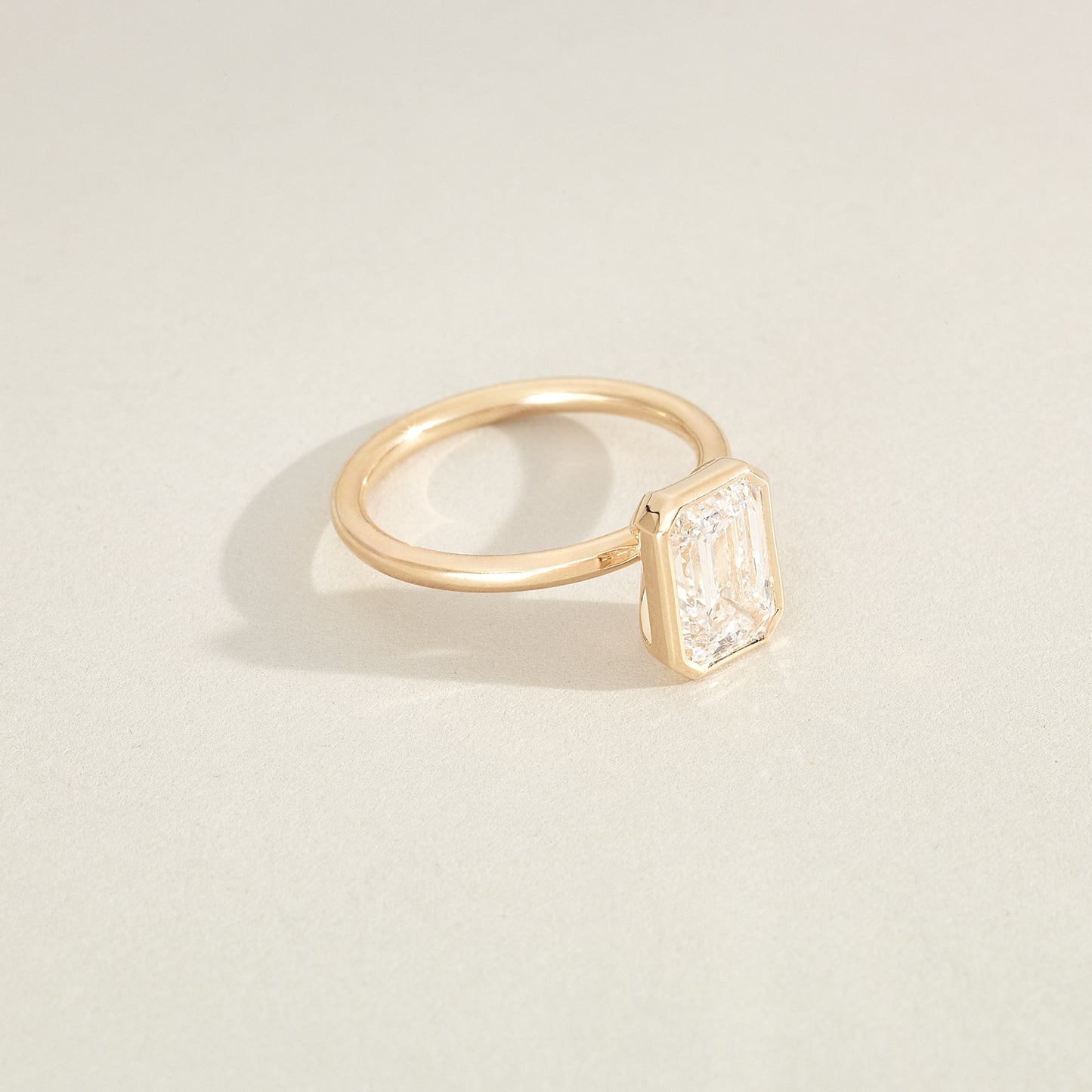 Gold ring with a diamond on a light beige background