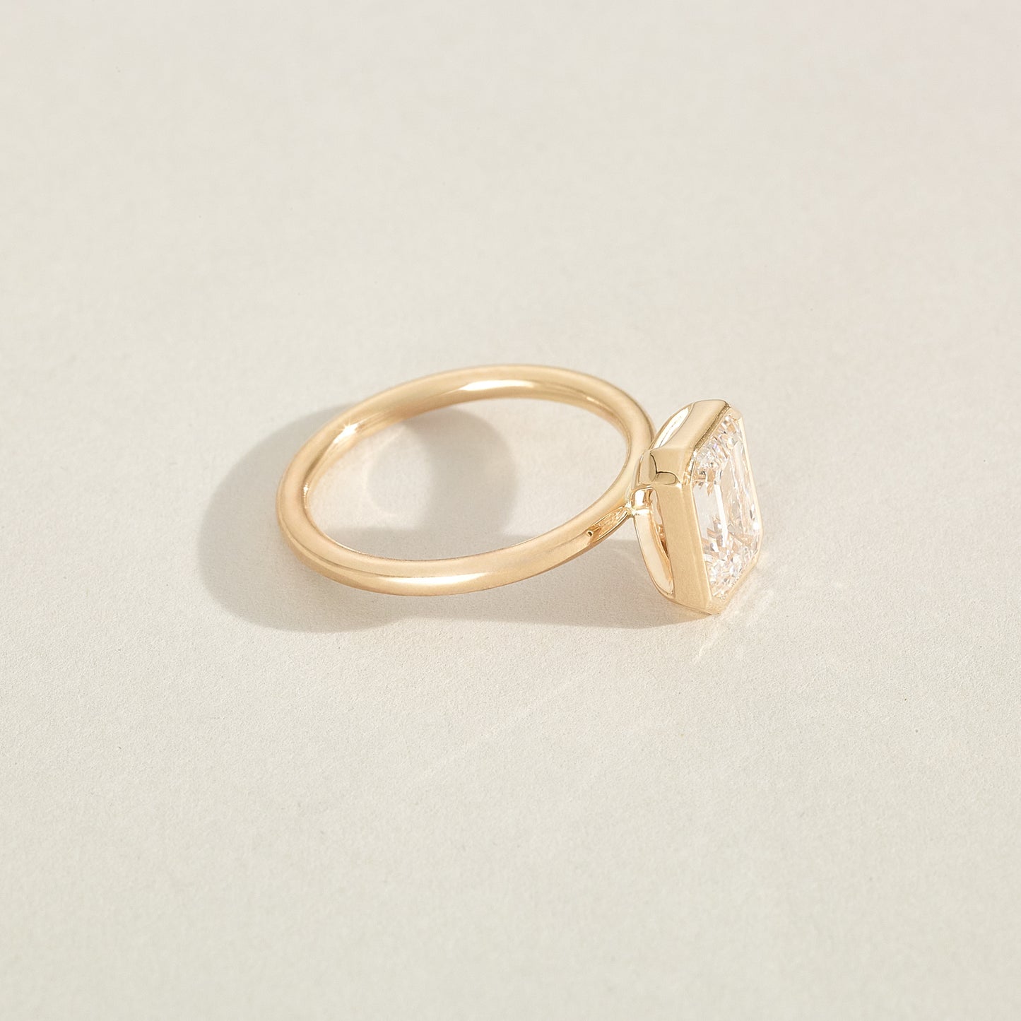 Gold ring with a diamond on a light beige background