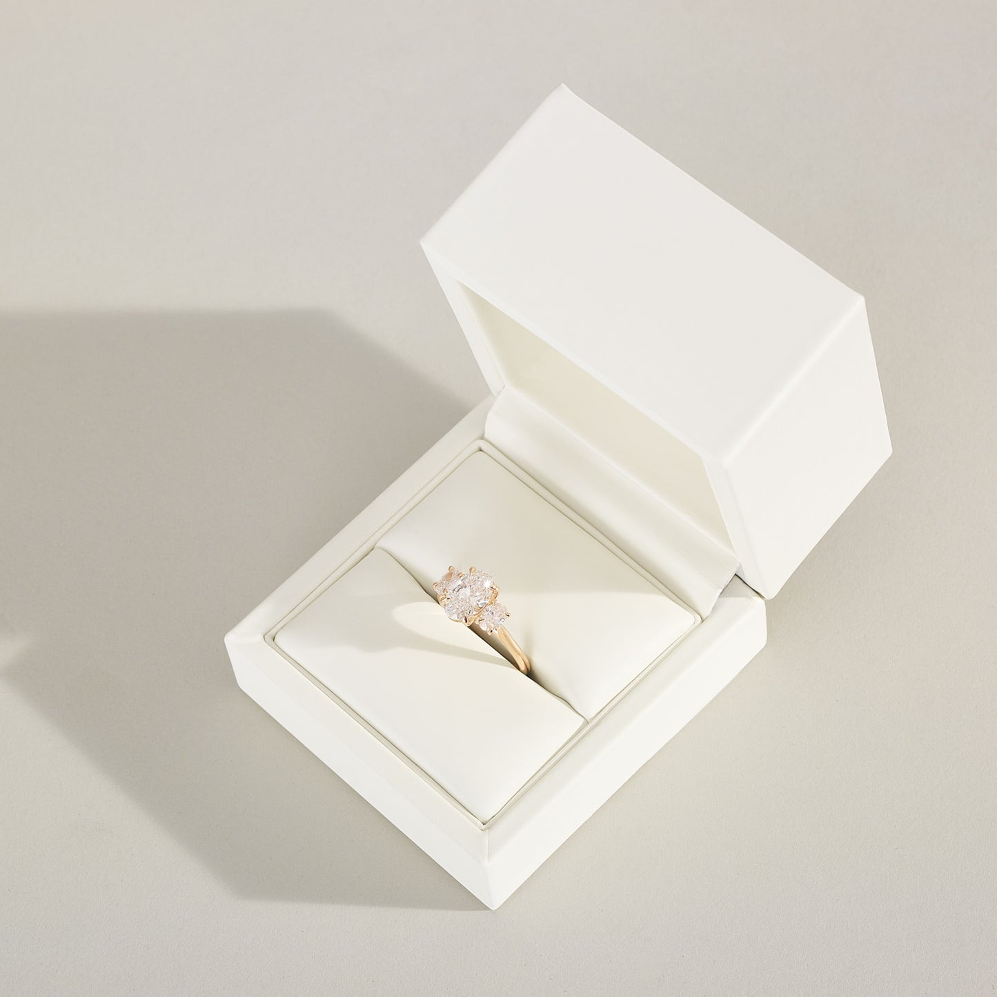 Open white jewelry box with a ring inside on a light gray background