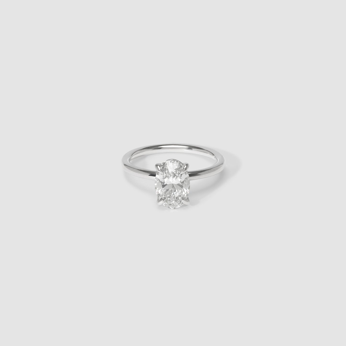 Elegant solitaire diamond ring on minimalist white background; luxury jewellery, sparkling central stone with sleek band.