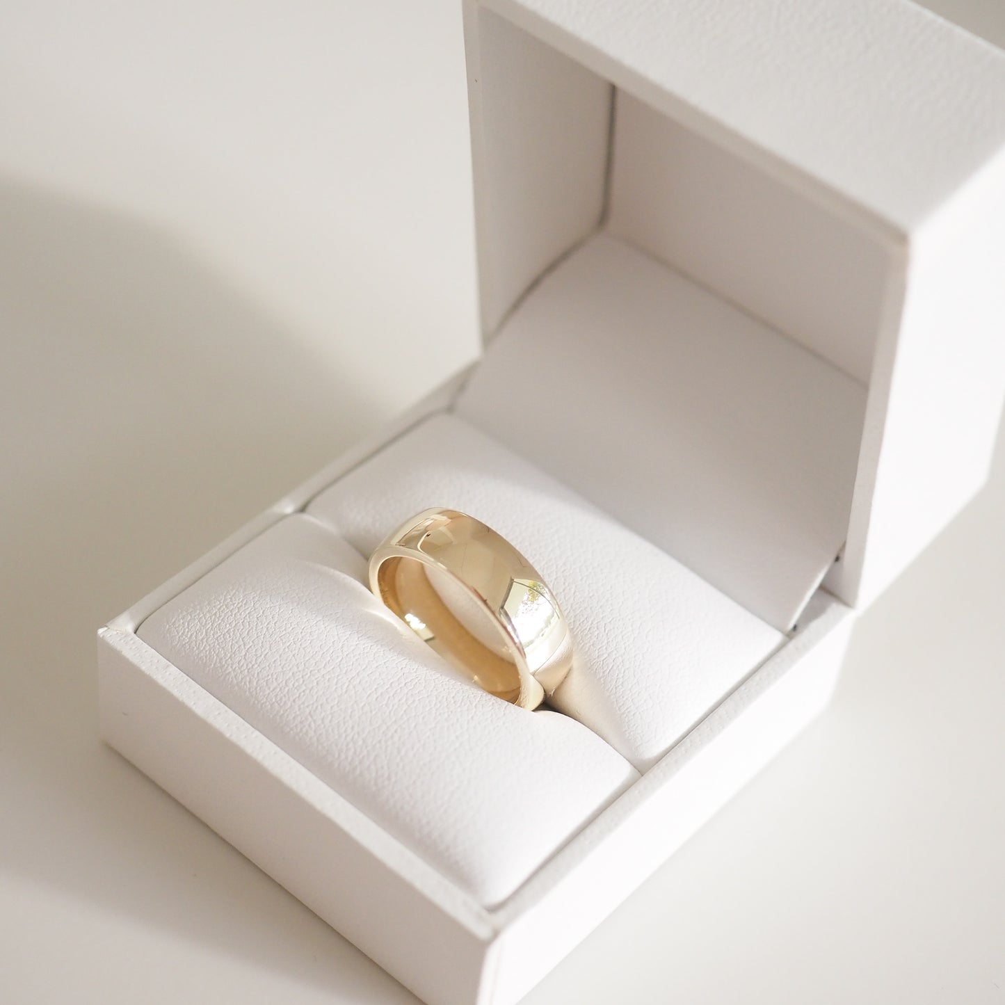 Gold ring in an open white jewellery box, showcasing luxury design and craftsmanship. Ideal for weddings or special occasions.