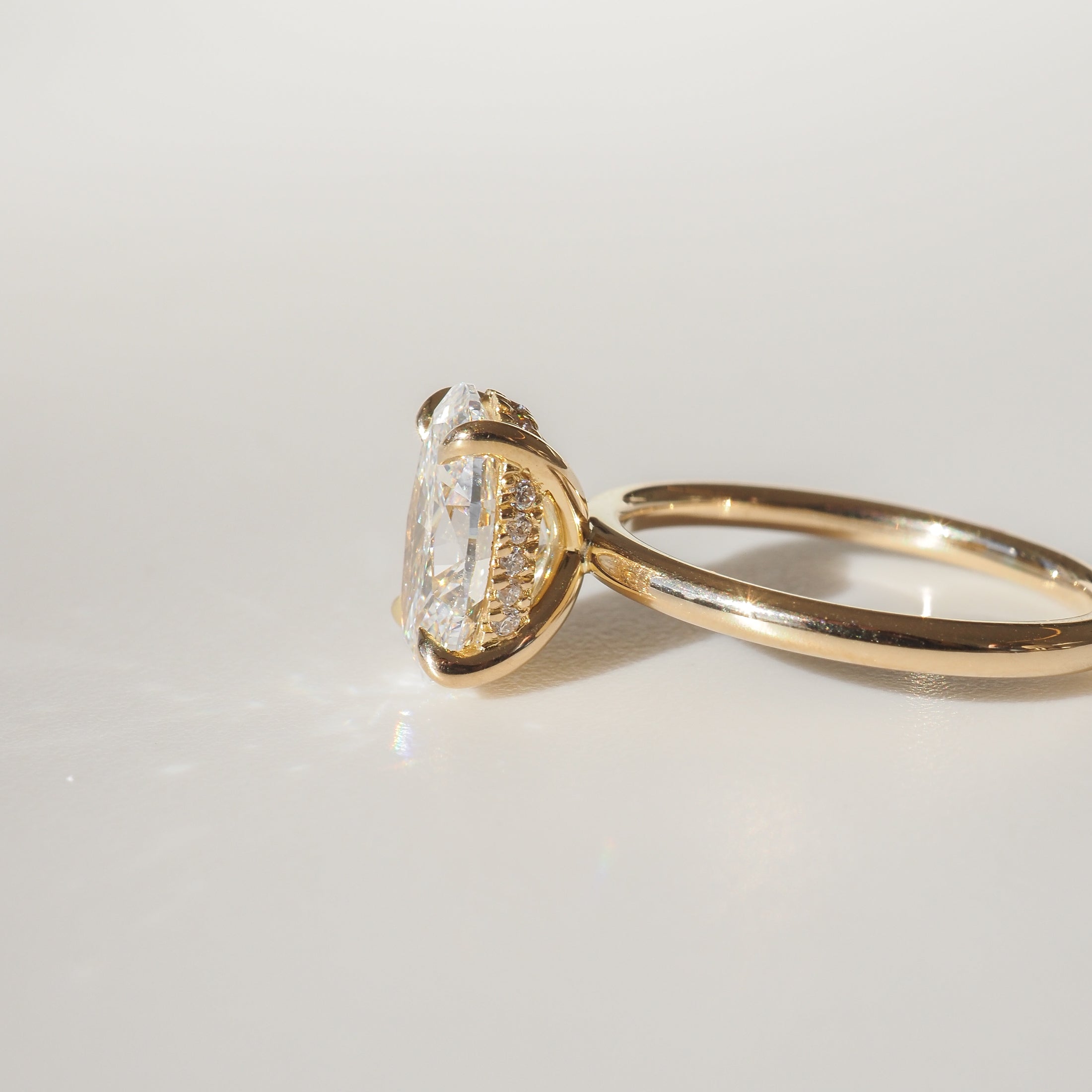 Gold ring featuring an oval-cut diamond in a raised setting, displayed against a neutral background, showcasing luxury jewellery craftsmanship.