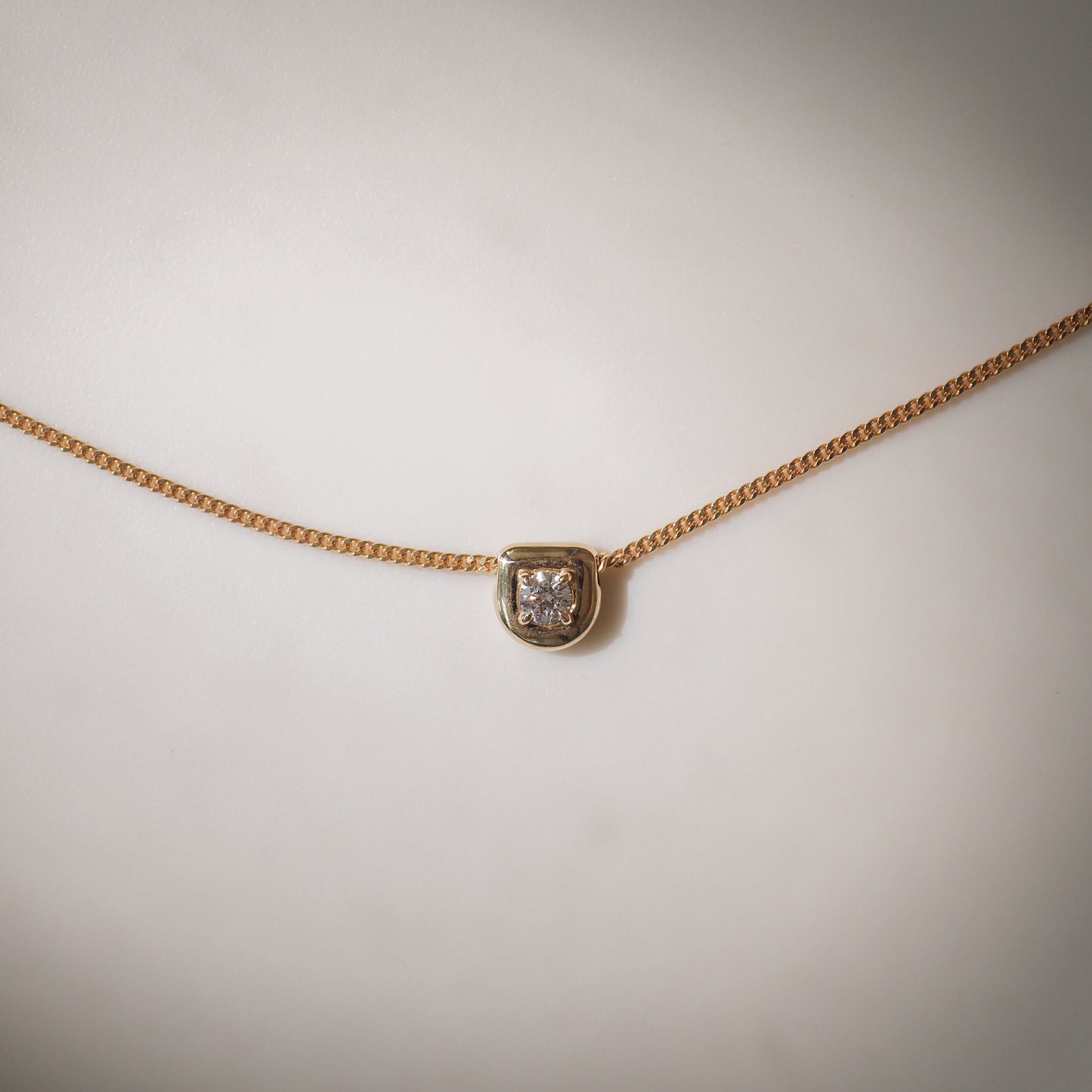 Gold chain necklace with a square diamond pendant set in gold, minimalist luxury jewellery design.
