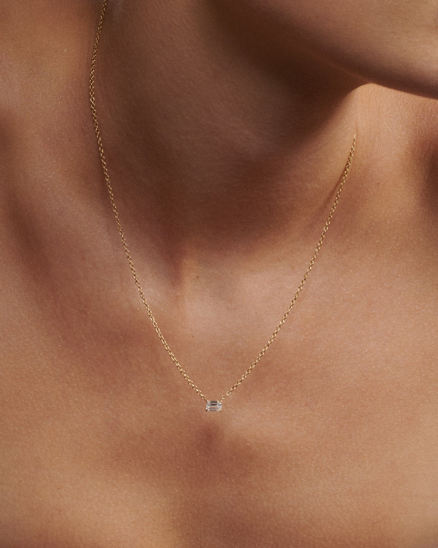 Gold necklace with a small pendant on a person's neck