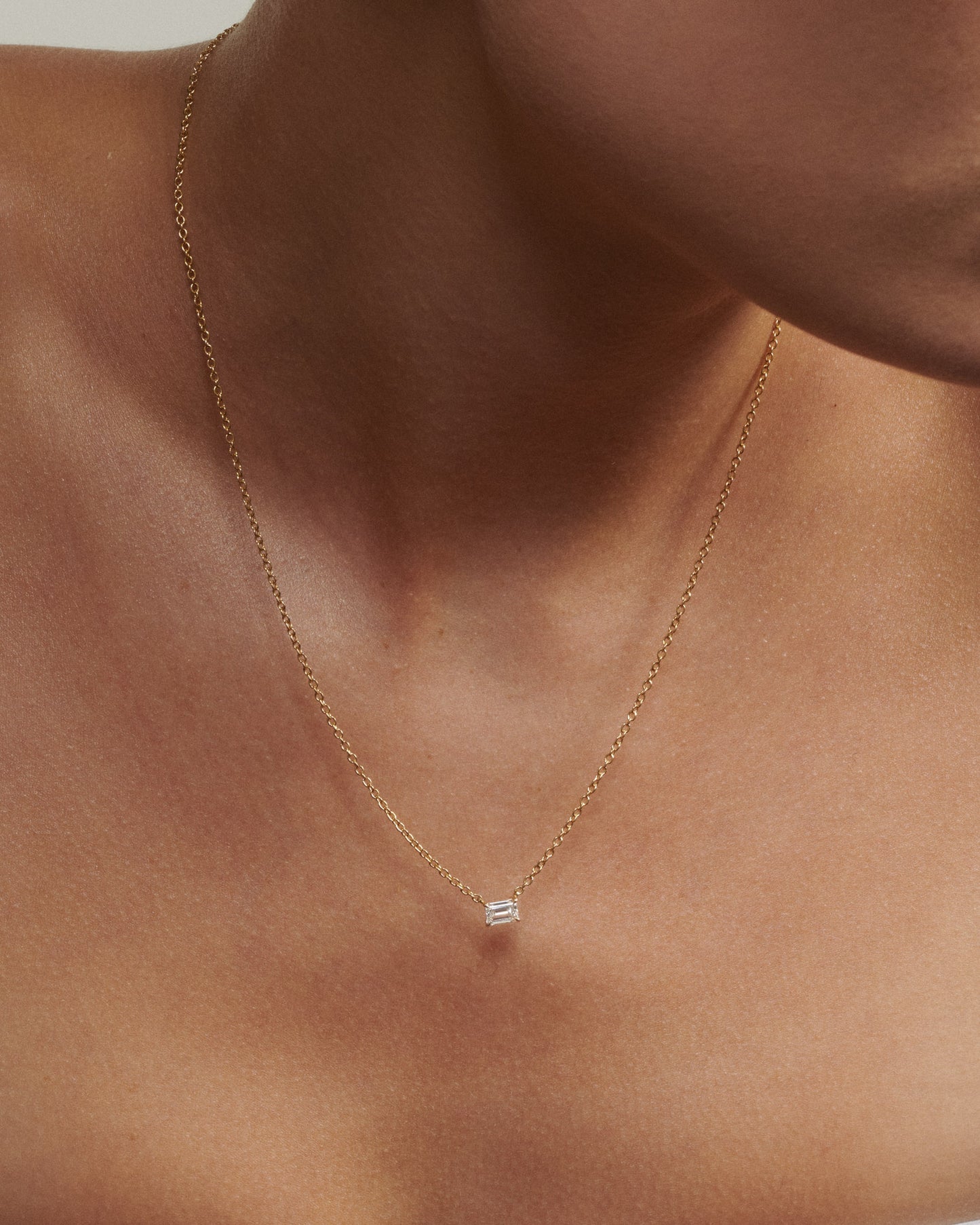 Gold necklace with a small pendant on a person's neck