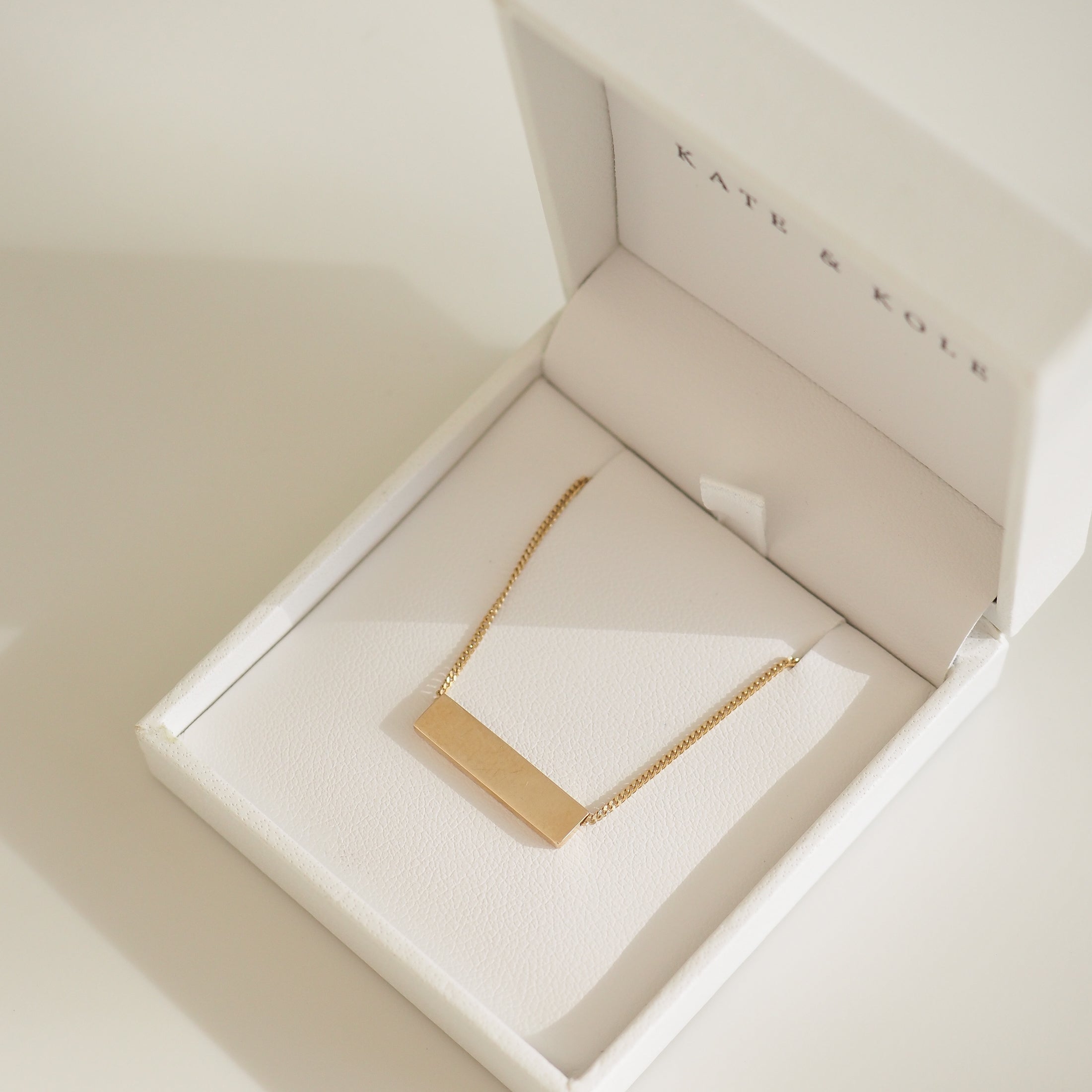 Gold rectangular pendant necklace in an elegant white Kate & Kole jewellery box. Perfect for luxury Australian fashion enthusiasts.