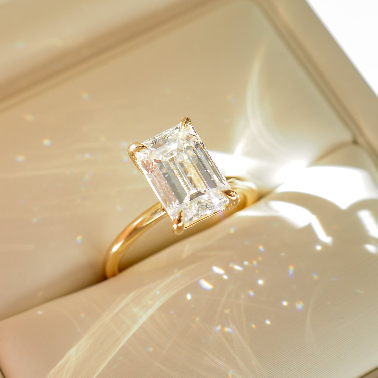 Emerald cut diamond ring with a gold band in a cream box. Luxurious, elegant jewellery design.