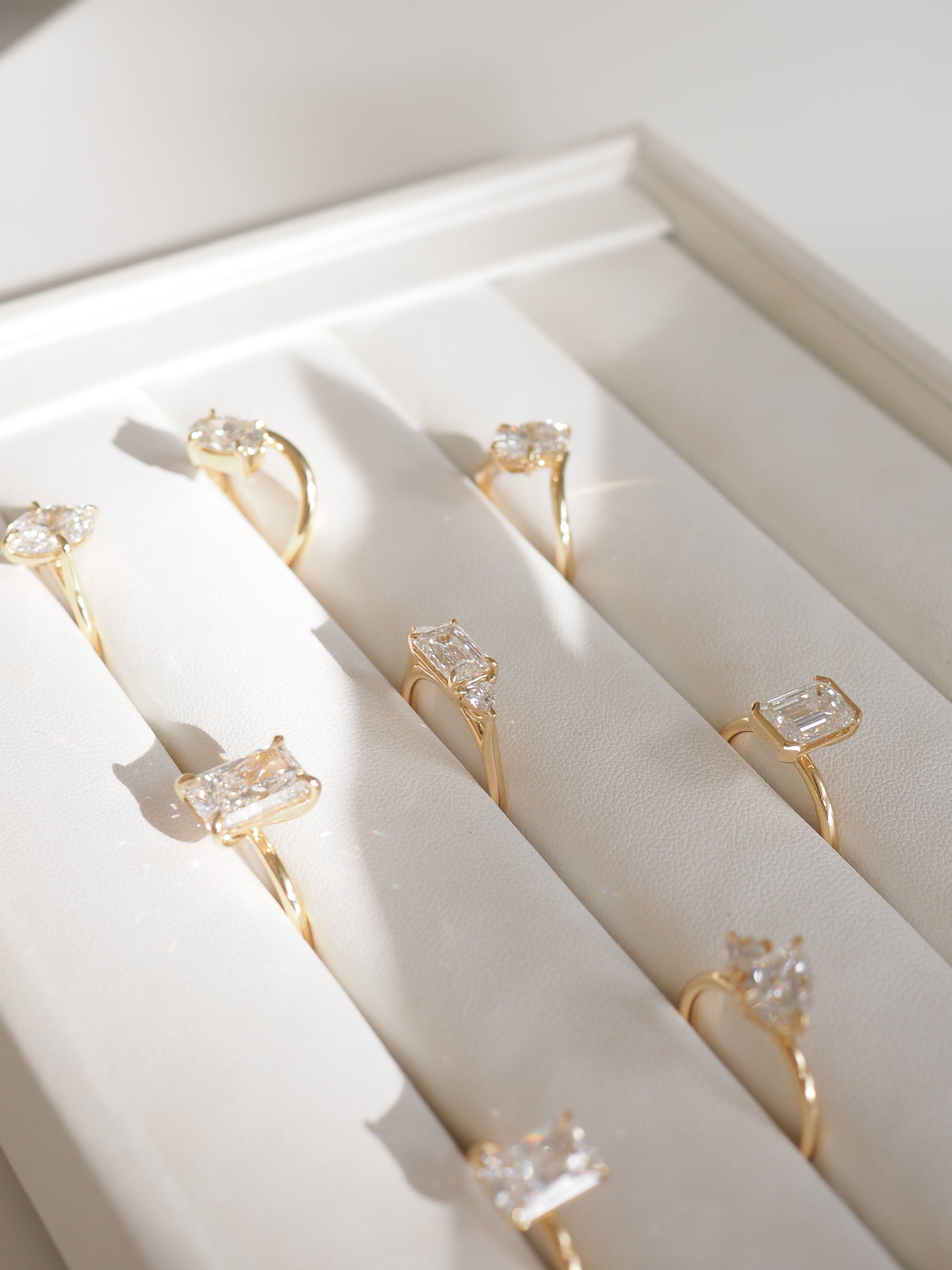 Elegant gold rings with large, rectangular cut diamonds beautifully displayed in a white jewellery box, capturing luxury and sophistication.