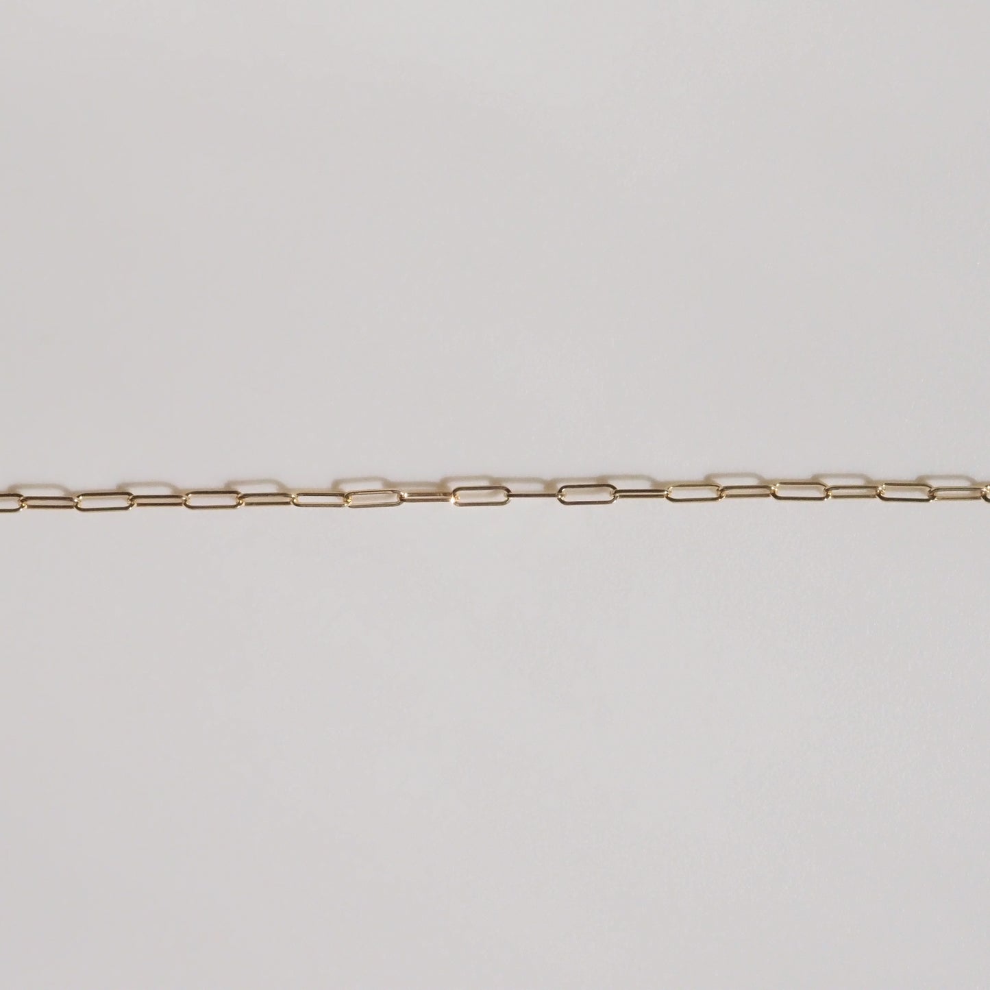 Delicate gold chain necklace displayed on a light background, featuring evenly spaced, rectangular links. Perfect for luxury jewellery enthusiasts.