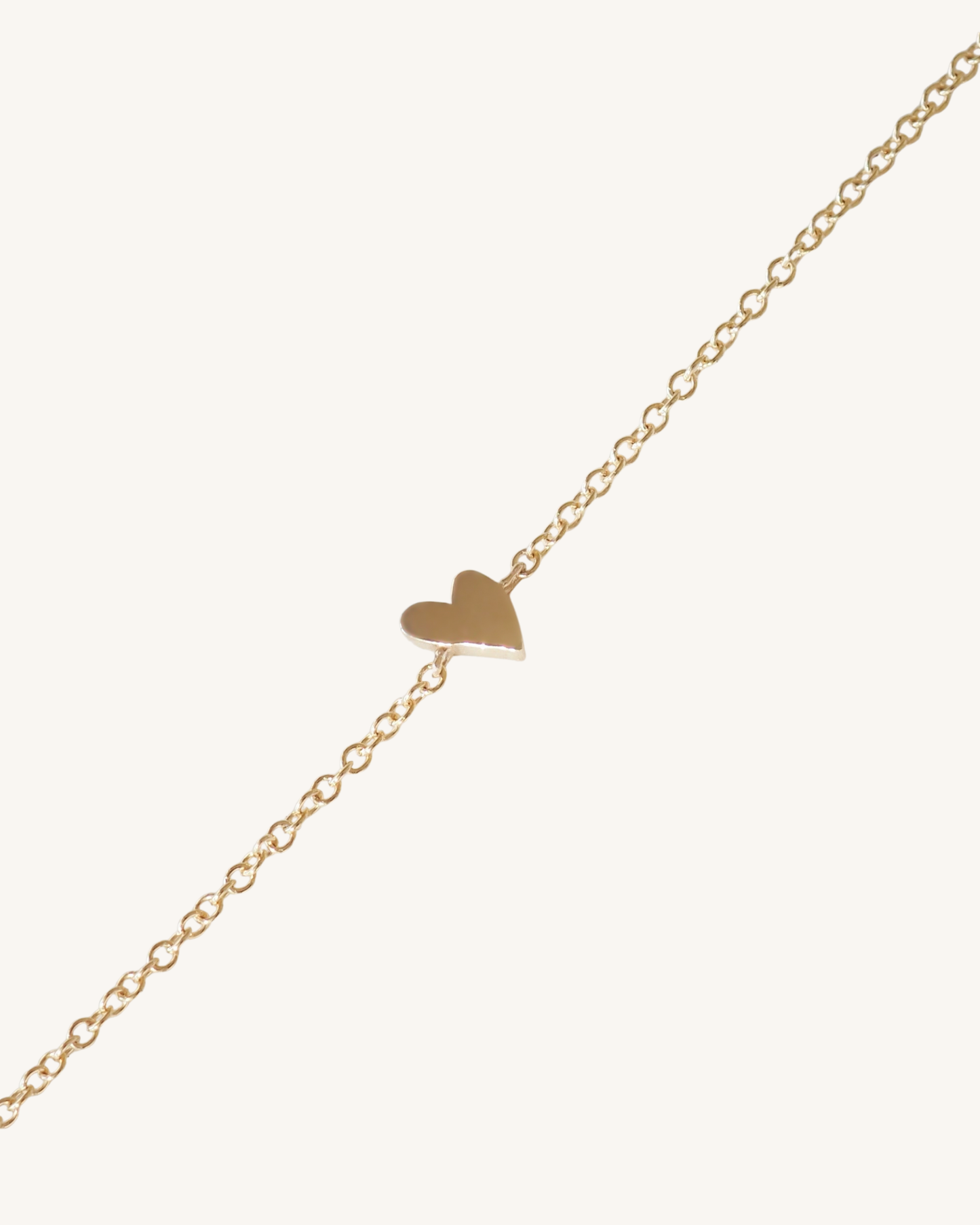 Gold heart-shaped pendant on a gold chain against a white background