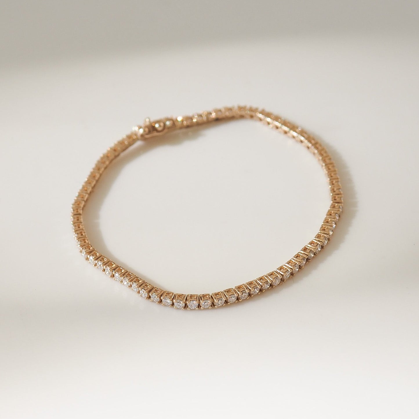 Yellow gold bracelet with clear stones on a light beige background