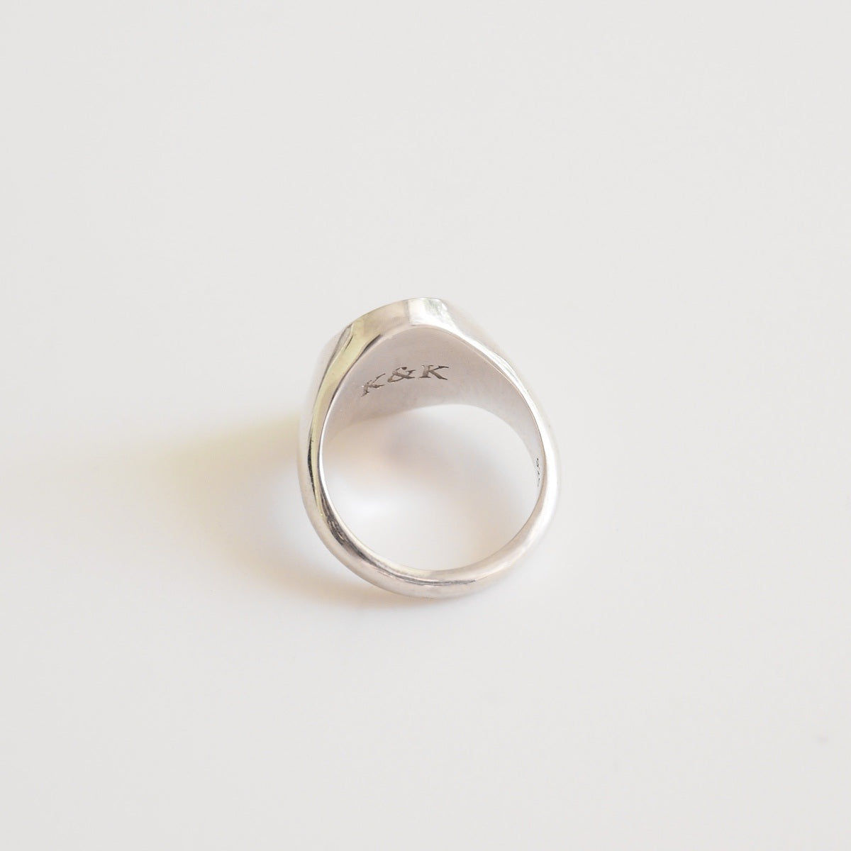 Silver ring with 'K&K' engraving on a light gray background