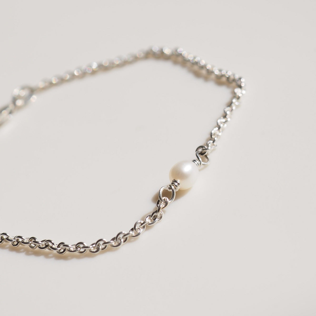 A flat lay of our fixed pearl bracelet on a cream background