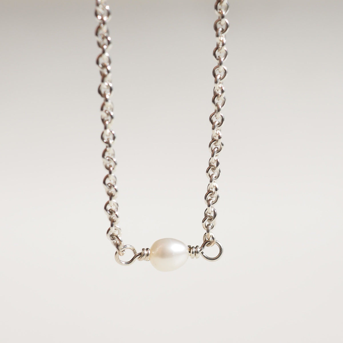 A flat lay of our fixed pearl bracelet on a cream background