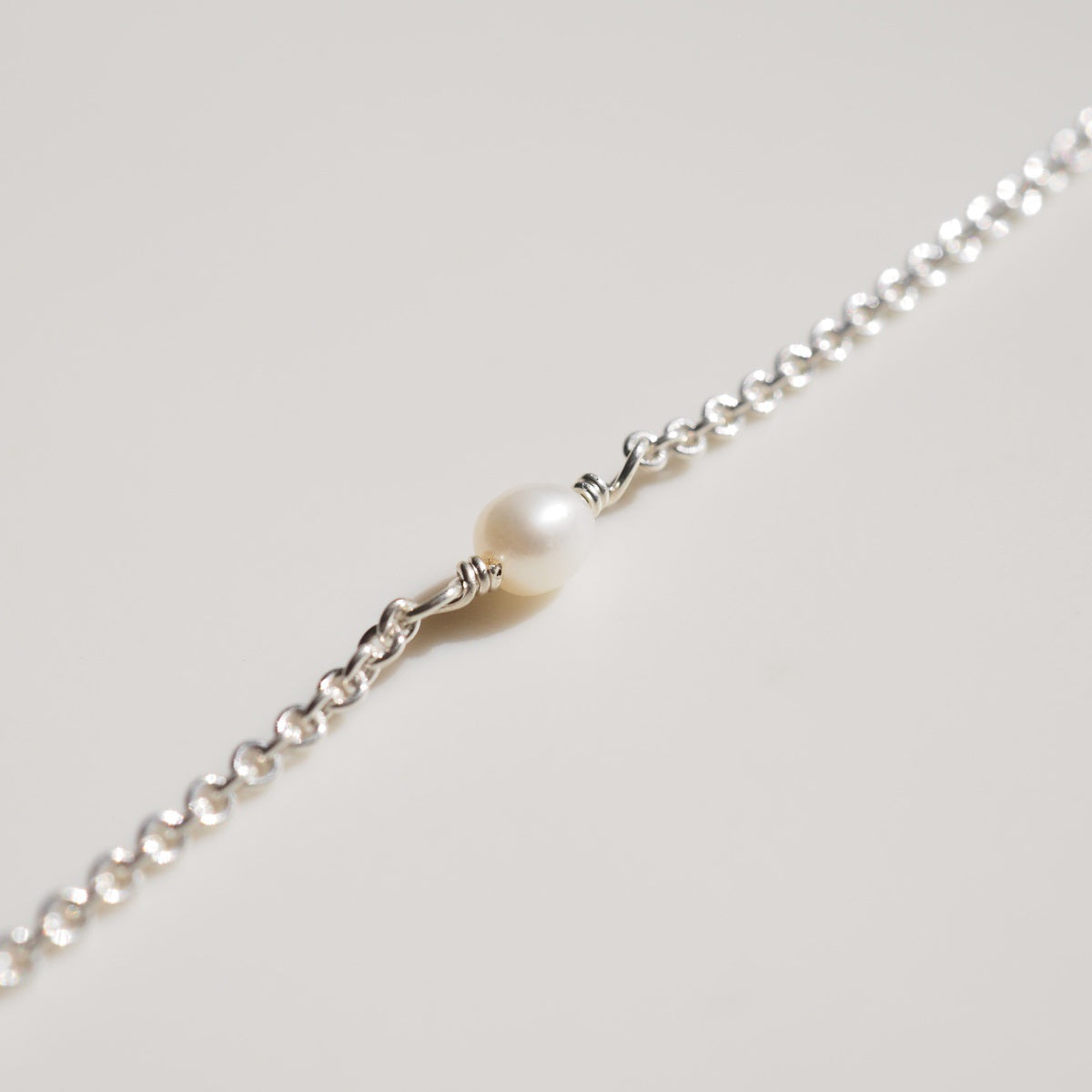 A flat lay of our fixed pearl bracelet on a cream background