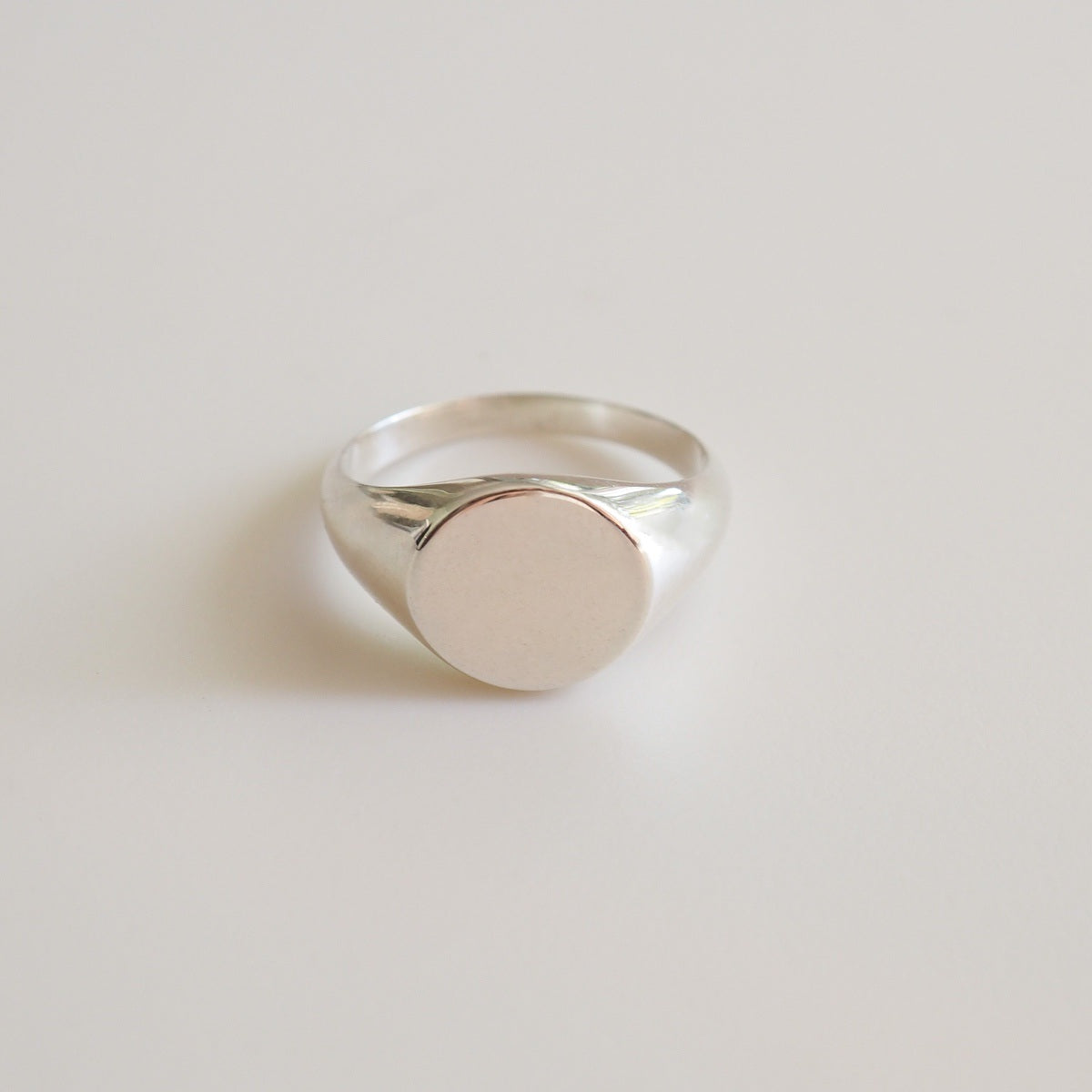 Silver ring with a round face on a light gray background