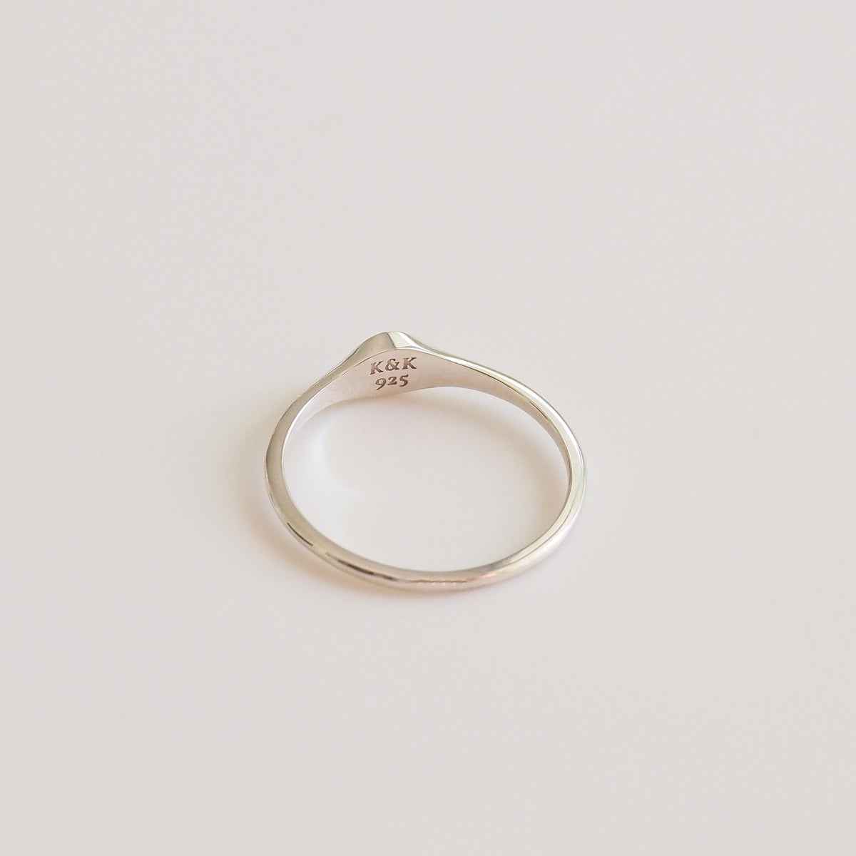 Silver ring with 'K&K' engraving on a light gray background