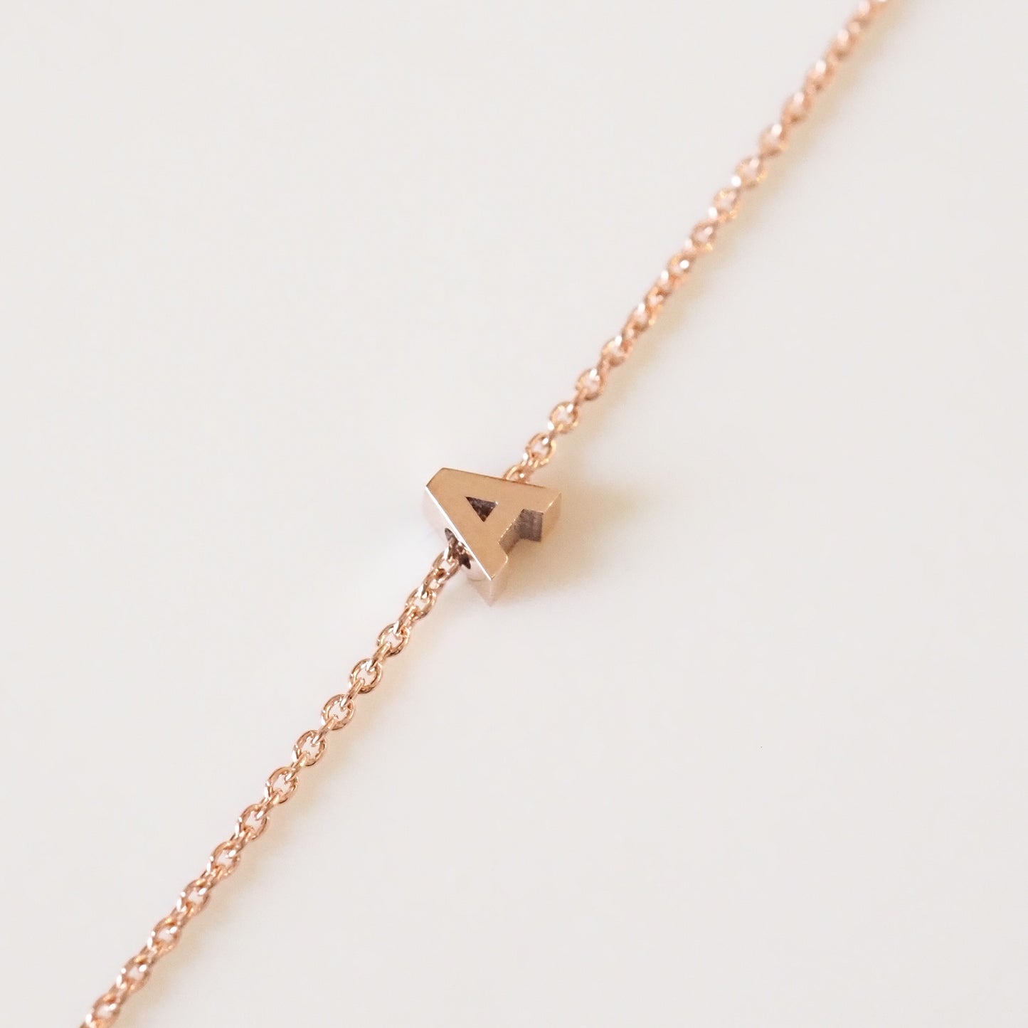 Rose gold necklace with a small pendant on a light background