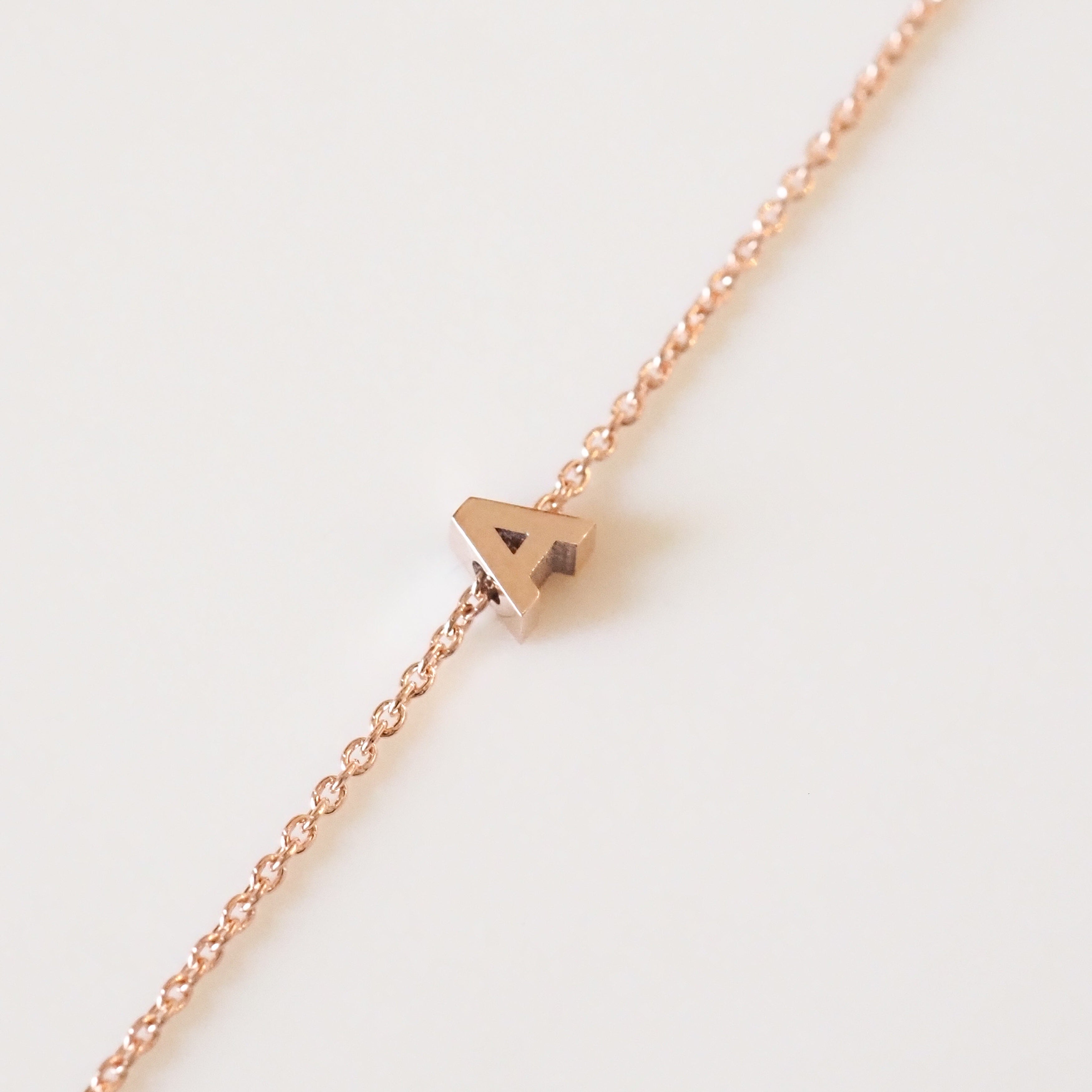 Rose gold necklace with a small pendant on a light background
