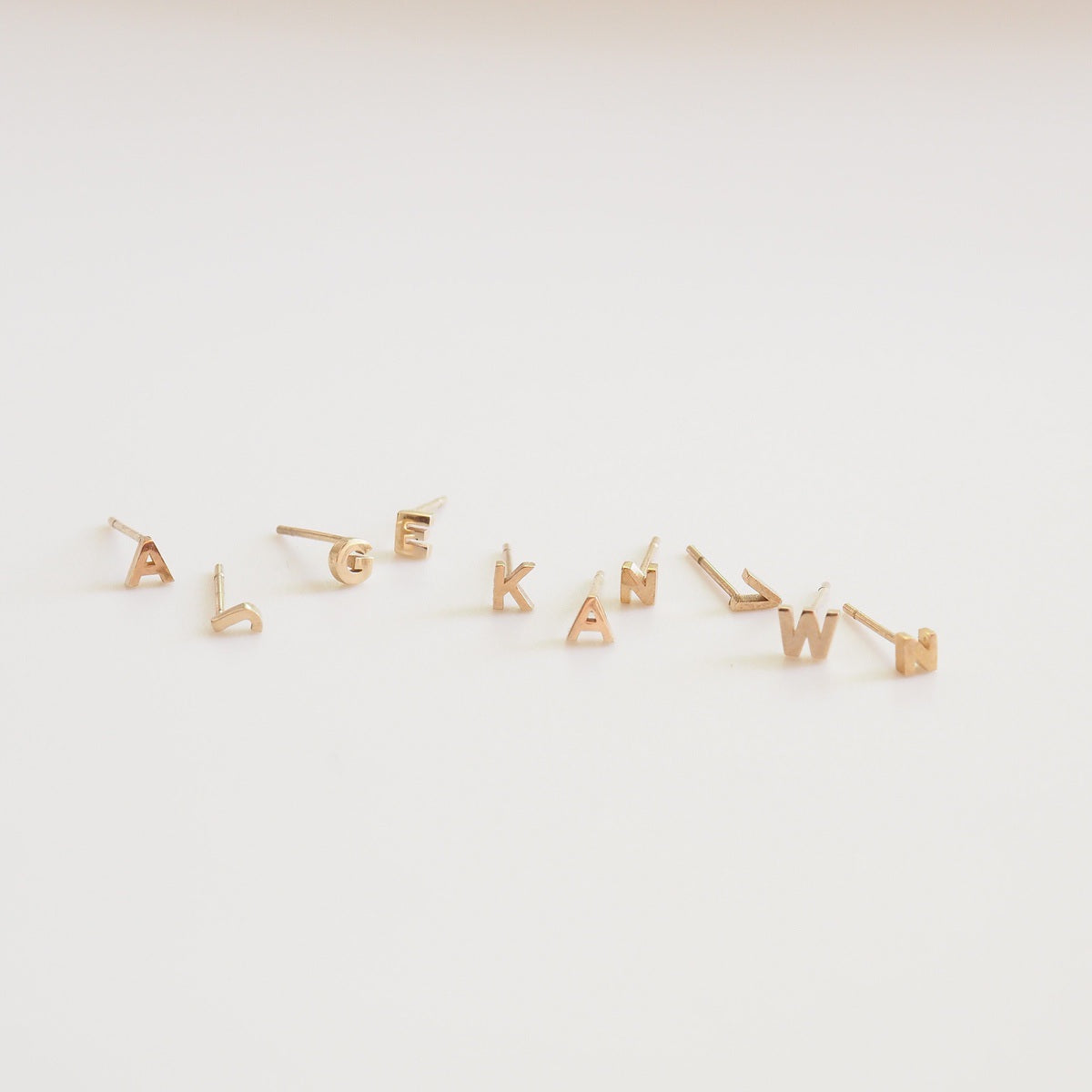 Gold letter earrings on a white background