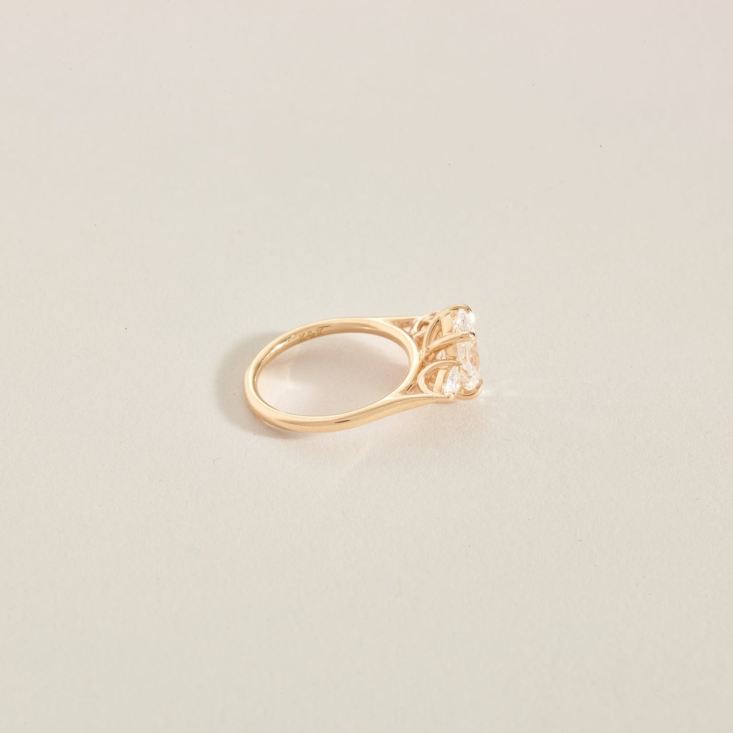 Gold ring with a 3 diamonds on a light beige background