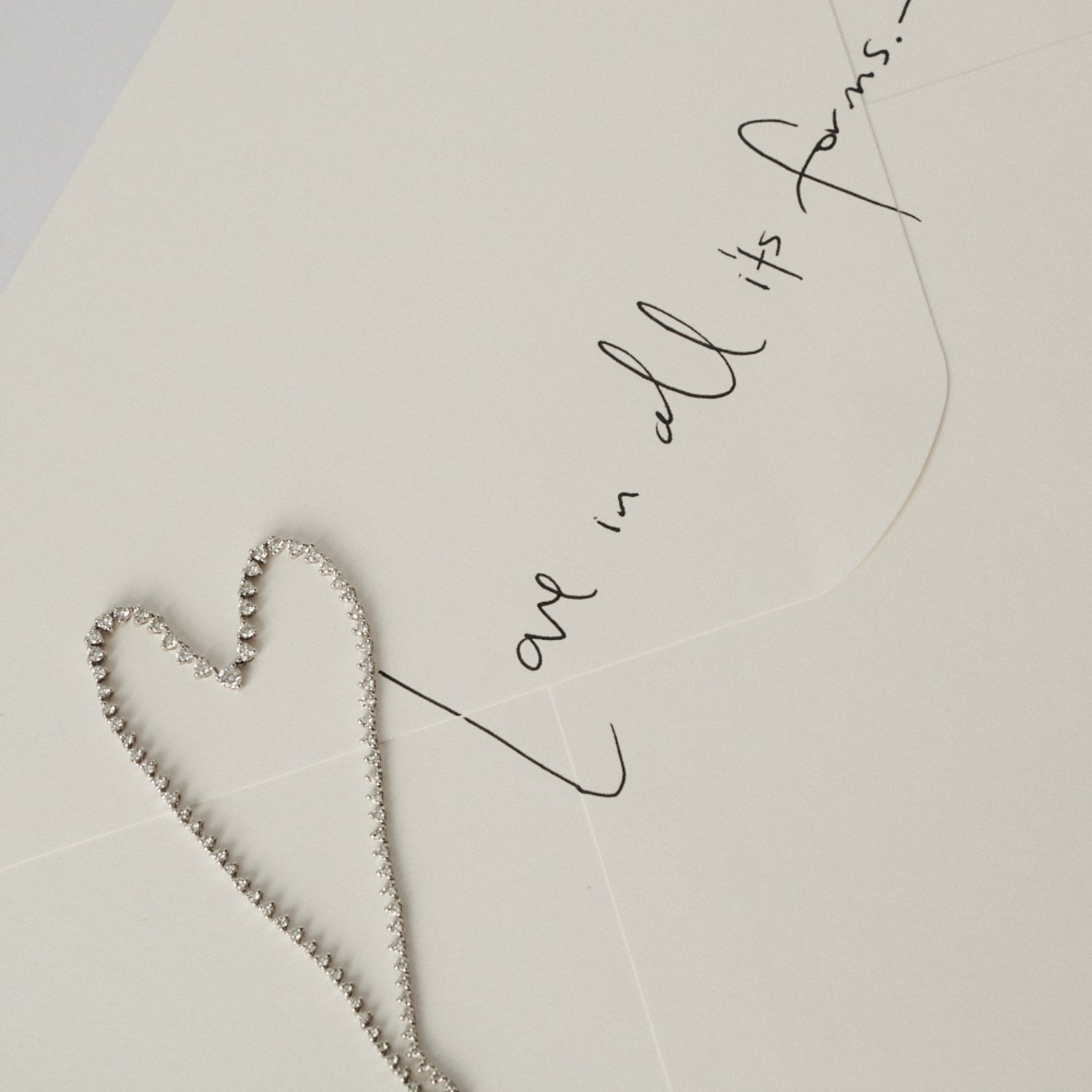 Heart-shaped necklace on a light background with cursive text