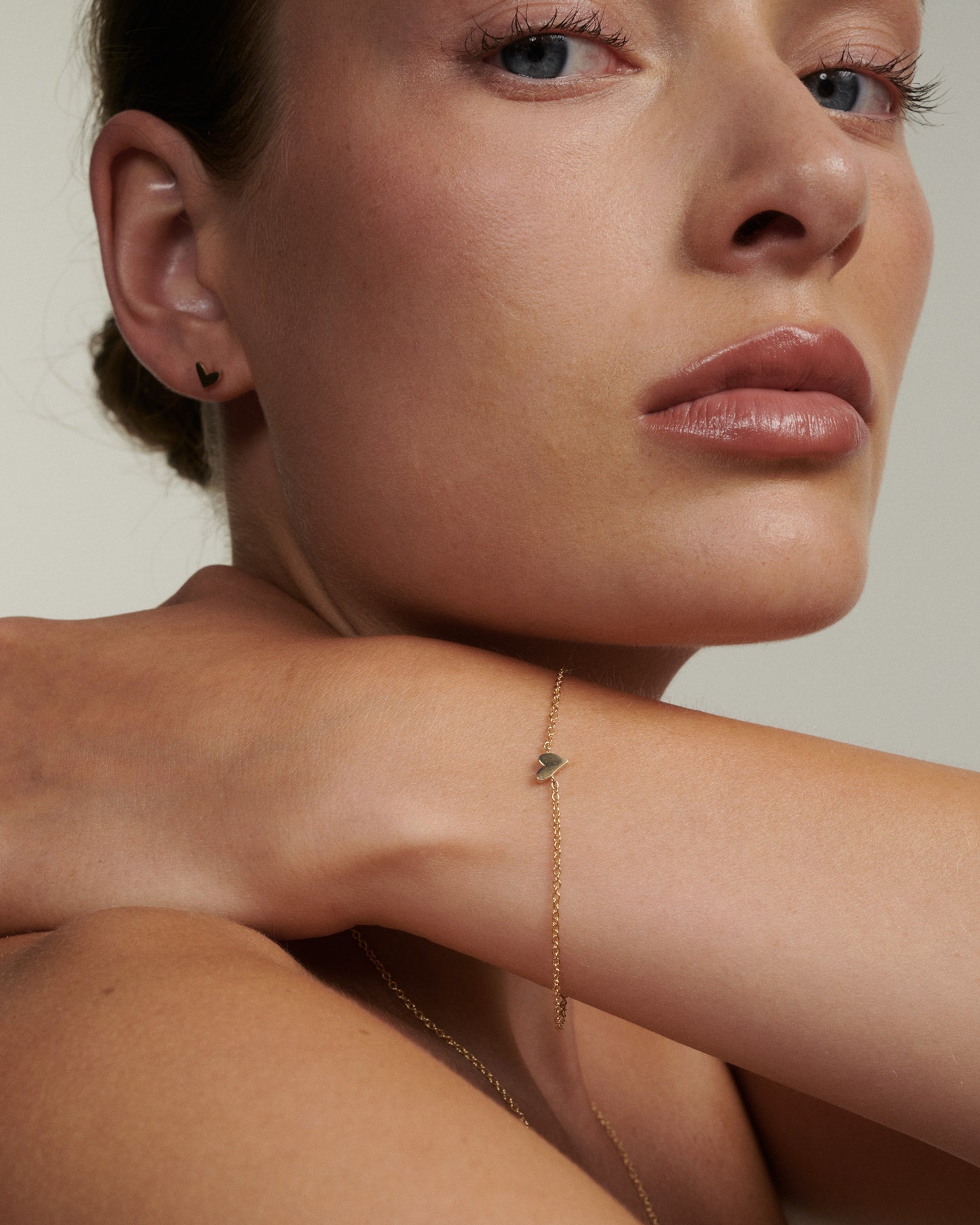 Close-up of a woman's face with a gold bracelet on her wrist.