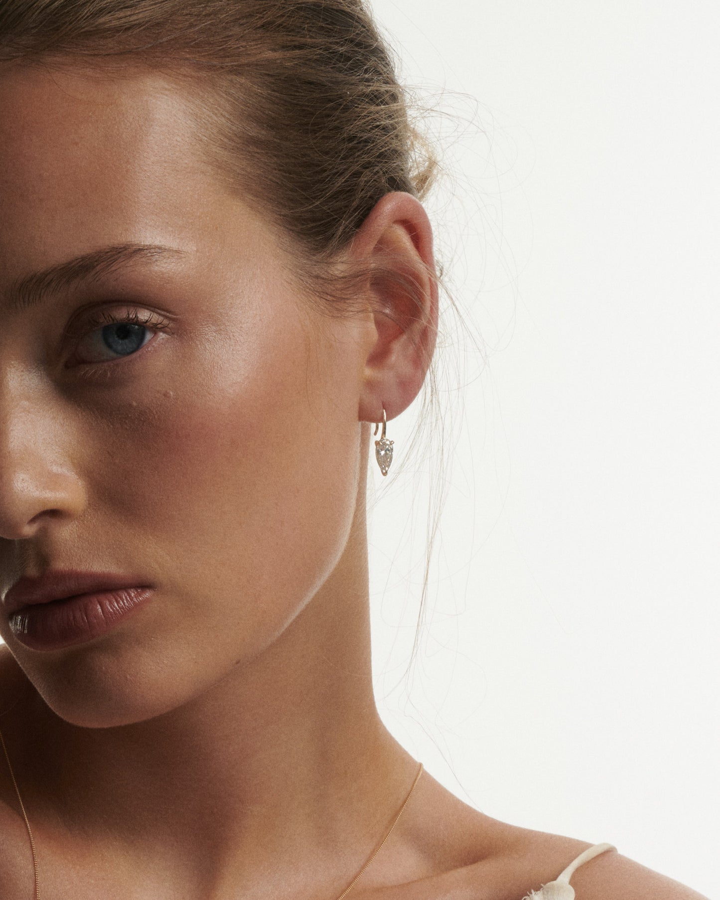 Close-up of a woman wearing a delicate earring with a white background