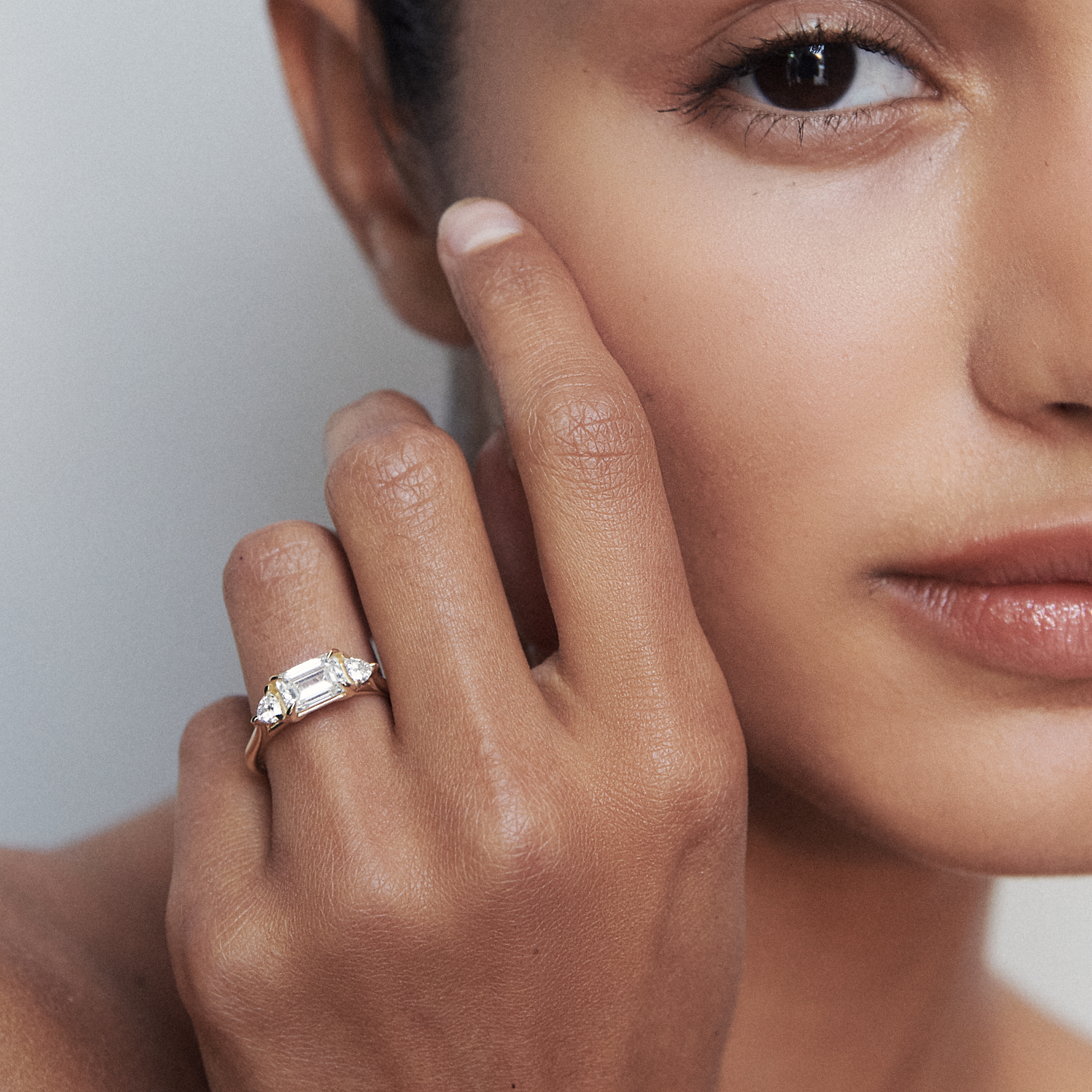 Woman's hand elegantly displaying a baguette-cut diamond ring. Luxurious jewellery piece on a warm skin tone, softly focused background.