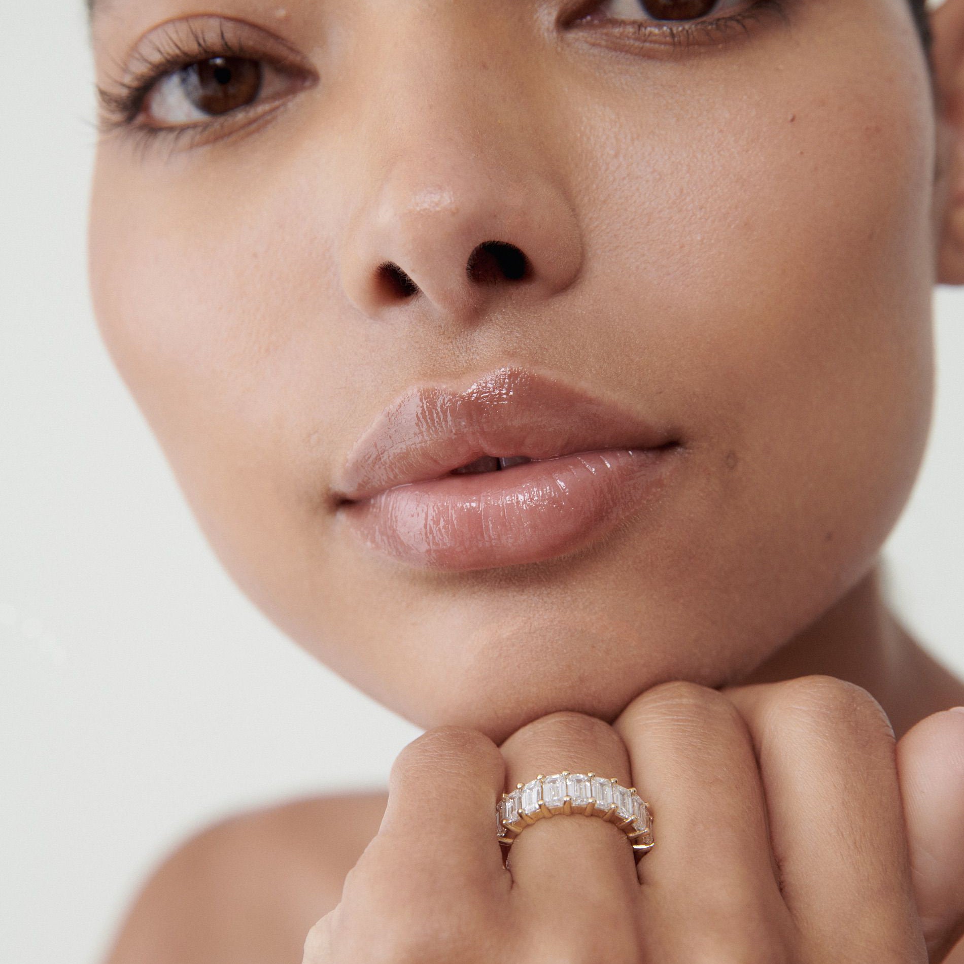 Close-up of a person wearing a luxurious diamond ring with baguette-cut stones, showcasing elegance and sophistication.[text overlay: Emerald] [text colour: #000000]
