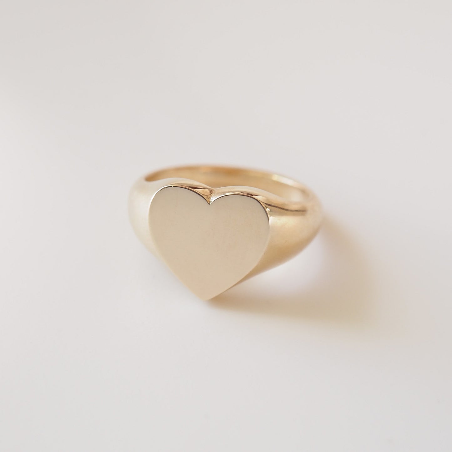 Gold heart-shaped ring on a light gray background