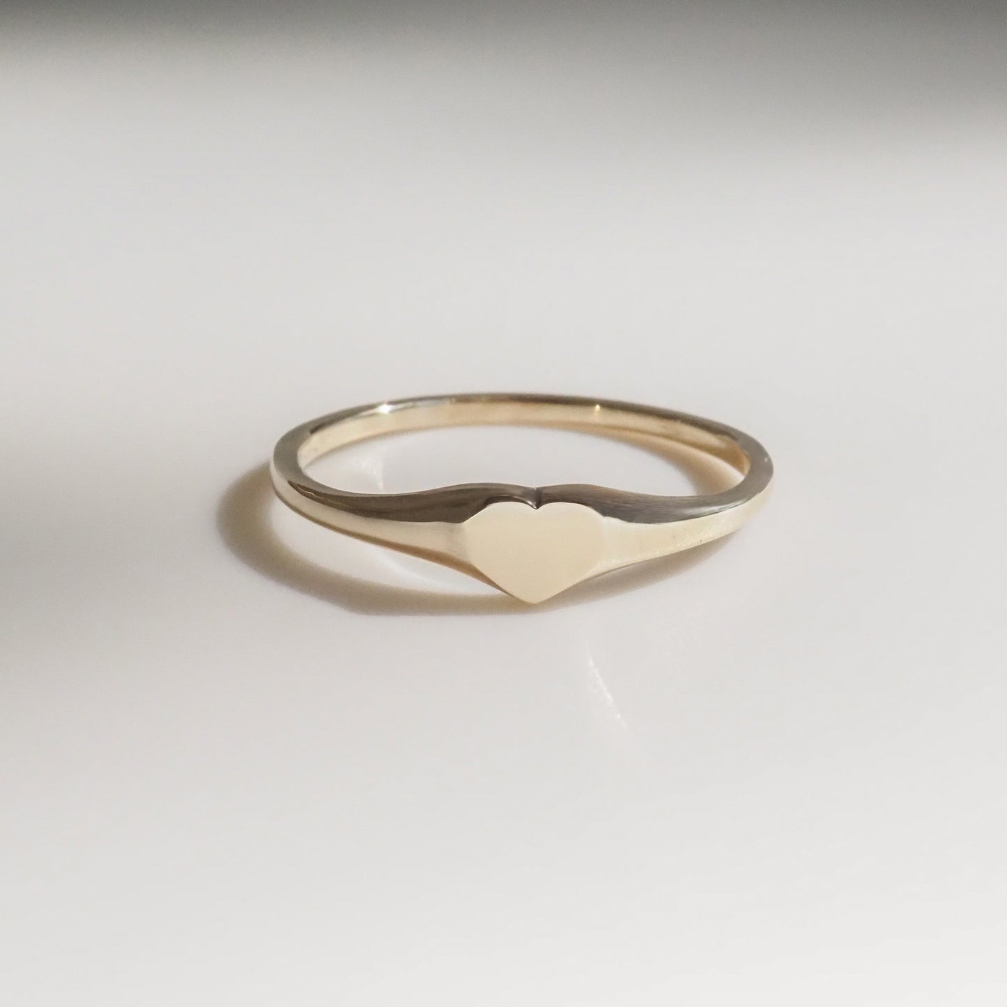 Delicate gold heart ring on a white background, featuring a minimalist design, perfect for luxury jewellery collectors.
