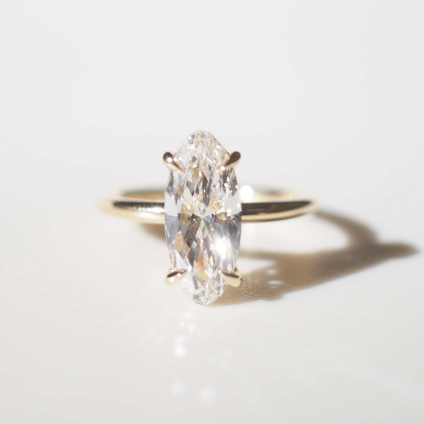 Gold ring with a Moval diamond on a light gray background
