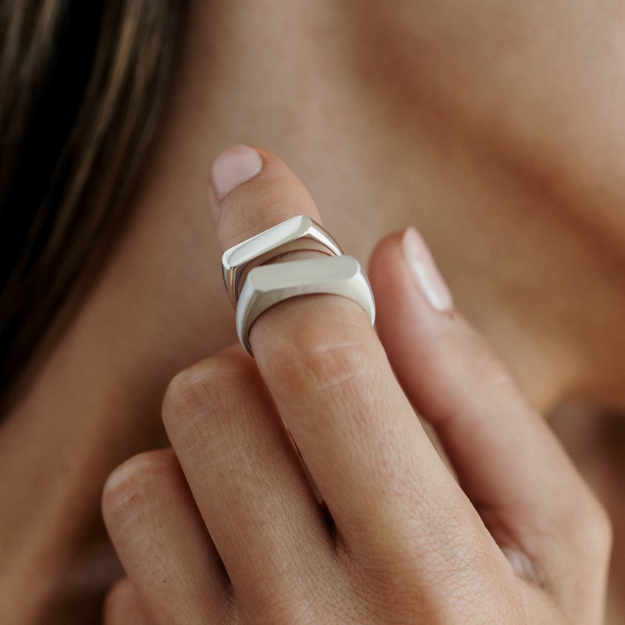 Close-up of a woman's hand wearing three elegant silver rings on her finger, showcasing minimalist luxury jewellery style.