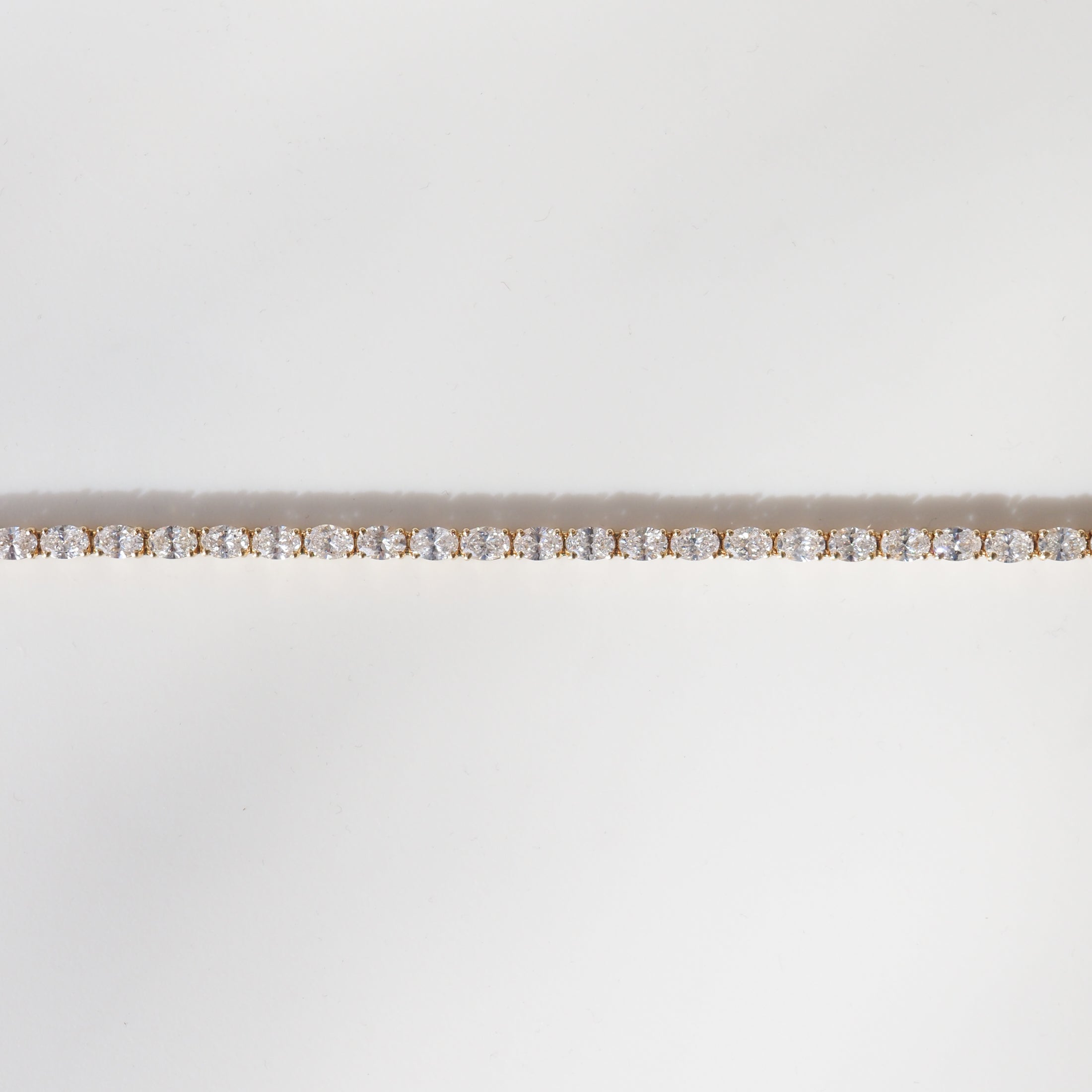 Elegant gold tennis bracelet adorned with sparkling round-cut diamonds, set against a plain white background.