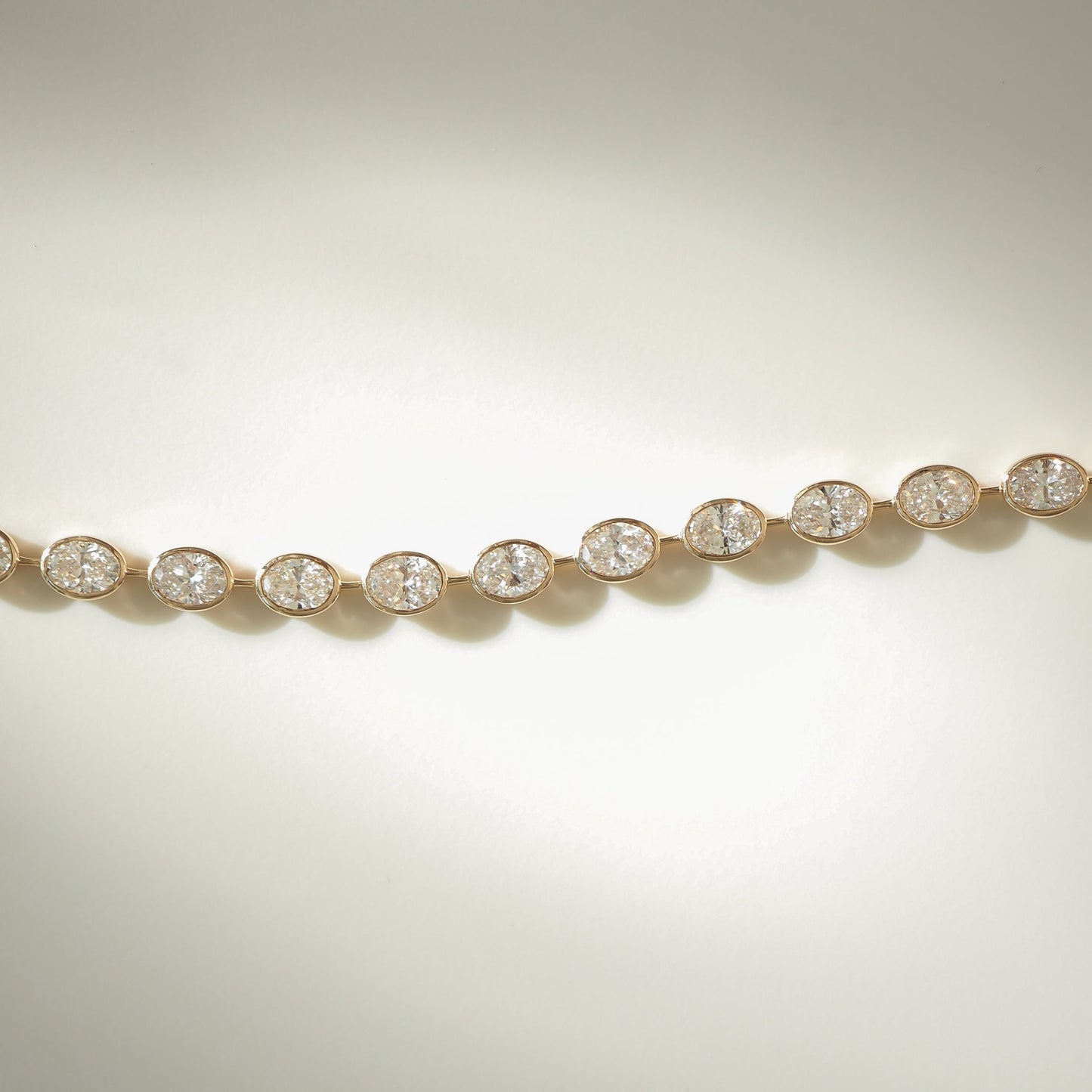 Gold bracelet with oval diamond settings against a soft light background, showcasing luxury jewellery design and elegance.
