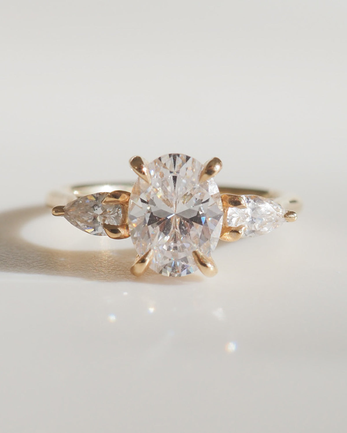 Elegant gold ring with an oval diamond centrepiece and two pear-shaped side diamonds, epitomising luxury jewellery design.