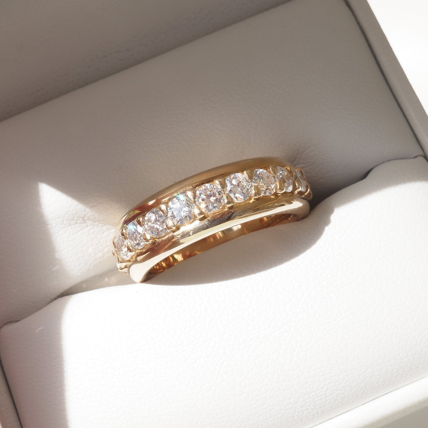 Gold ring with brilliant diamonds set across the band, elegantly displayed in a jewellery box. Luxurious and sophisticated.