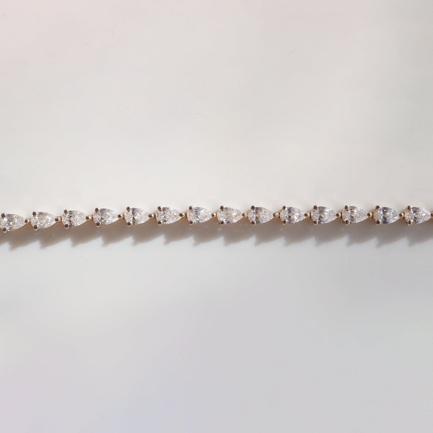 Elegant diamond bracelet with marquise-cut stones set in gold, displayed on a soft, neutral background. Luxurious jewellery detail.