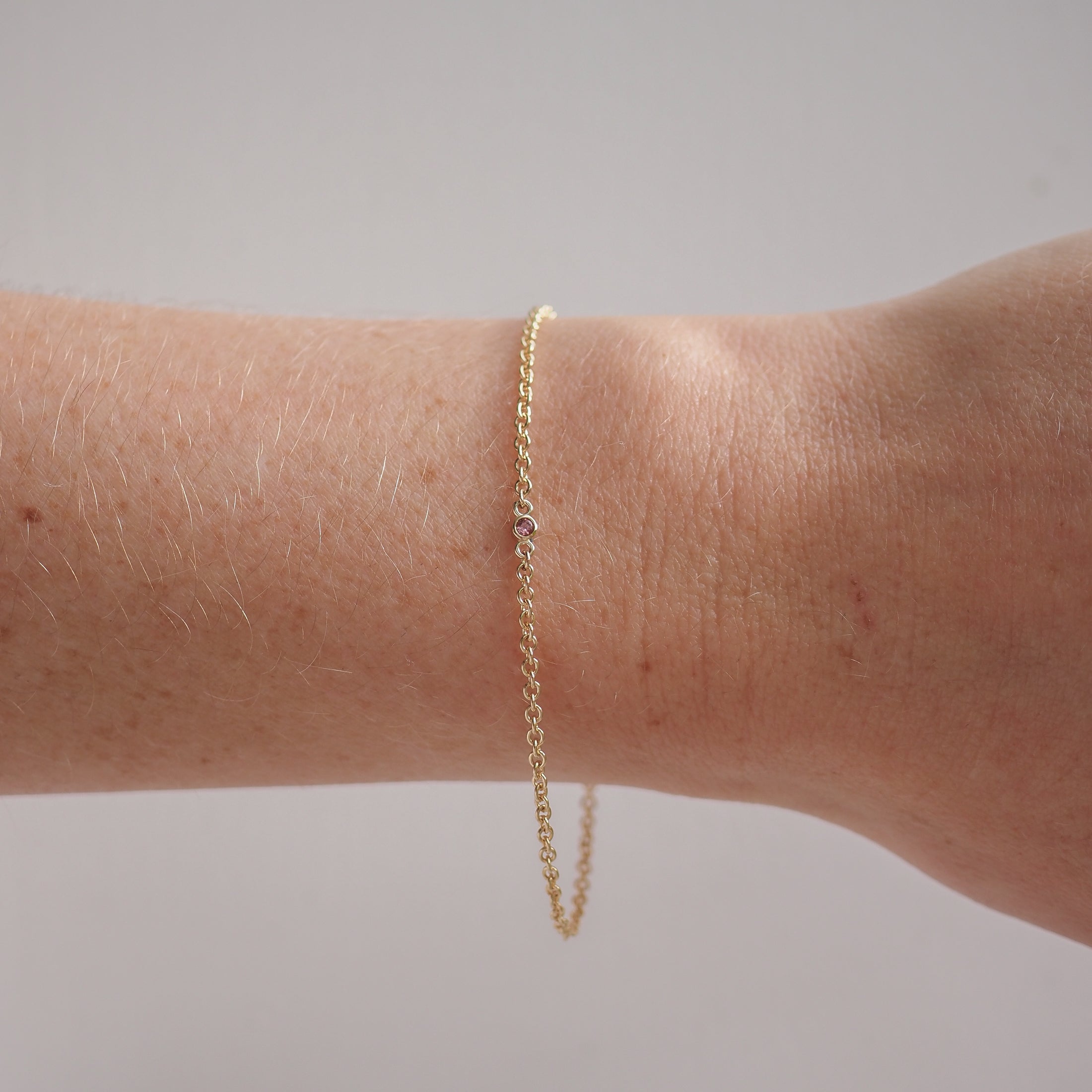 Delicate gold bracelet with a single small gemstone on a wrist, showcasing minimalist and elegant jewellery design. Perfect for luxury fashion.