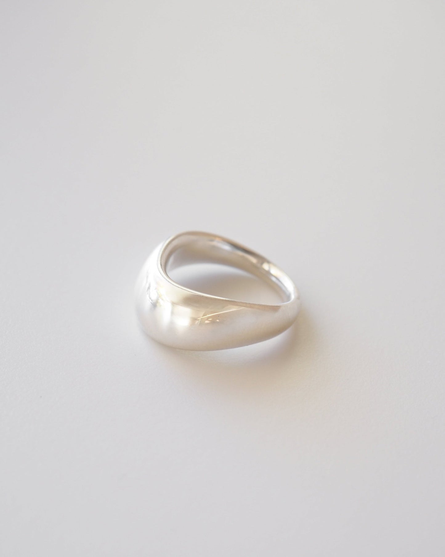 A bold silver curved ring on a white background