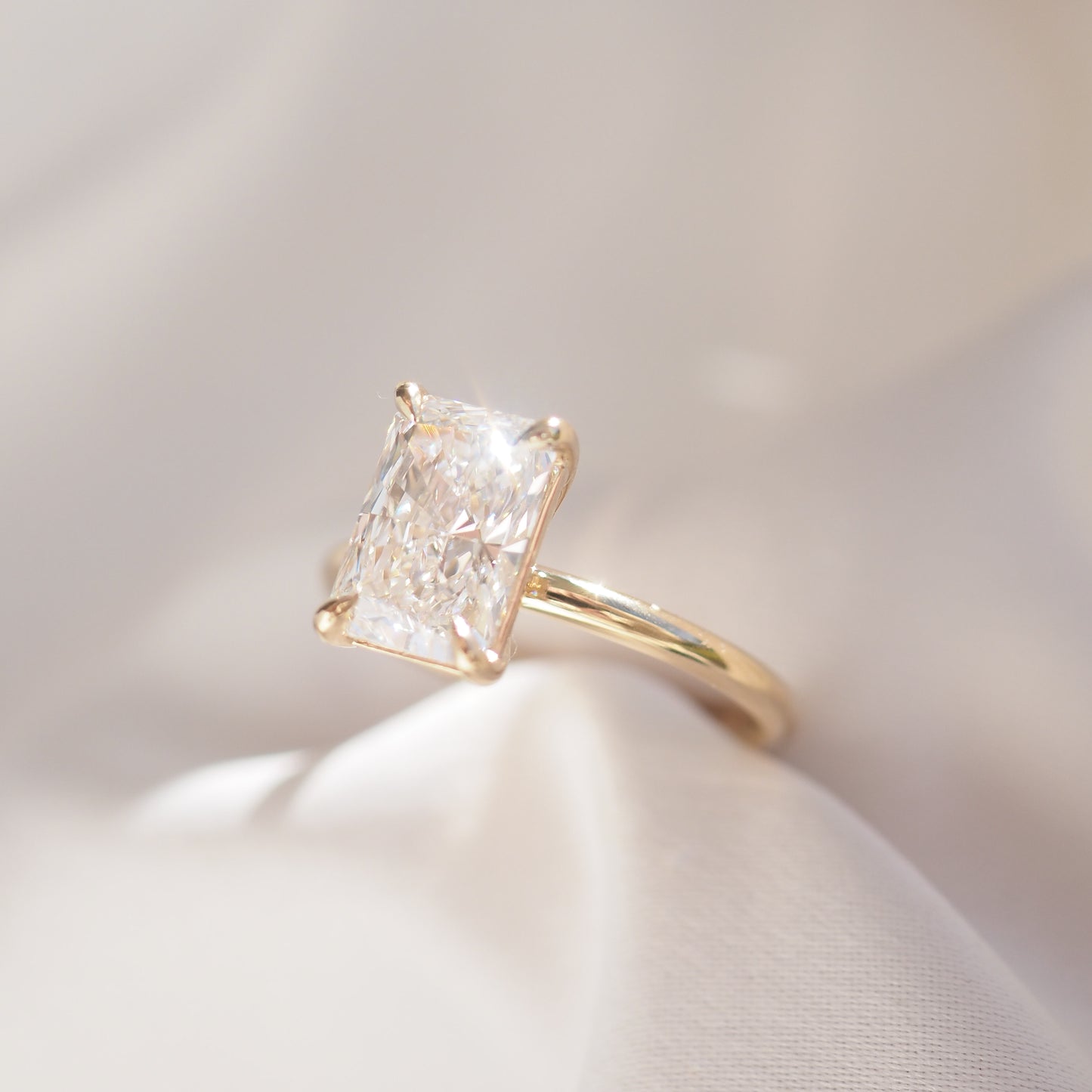 Gold ring with a large diamond on a soft white background